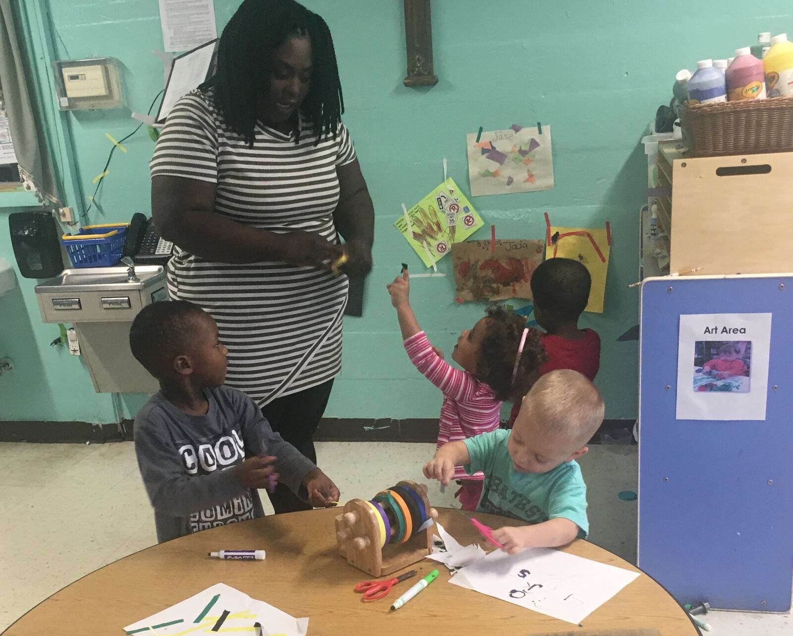 Chanie Corbitt, a preschool teacher at Dayton Christian Center on West Riverview Avenue, helps students with academic and fine-motor skill activities Friday, Oct. 21, 2016. The students wrote letters and numbers with the help of stencils, then used scissors to cut colored tape so they could hang up their papers. JEREMY P. KELLEY / STAFF