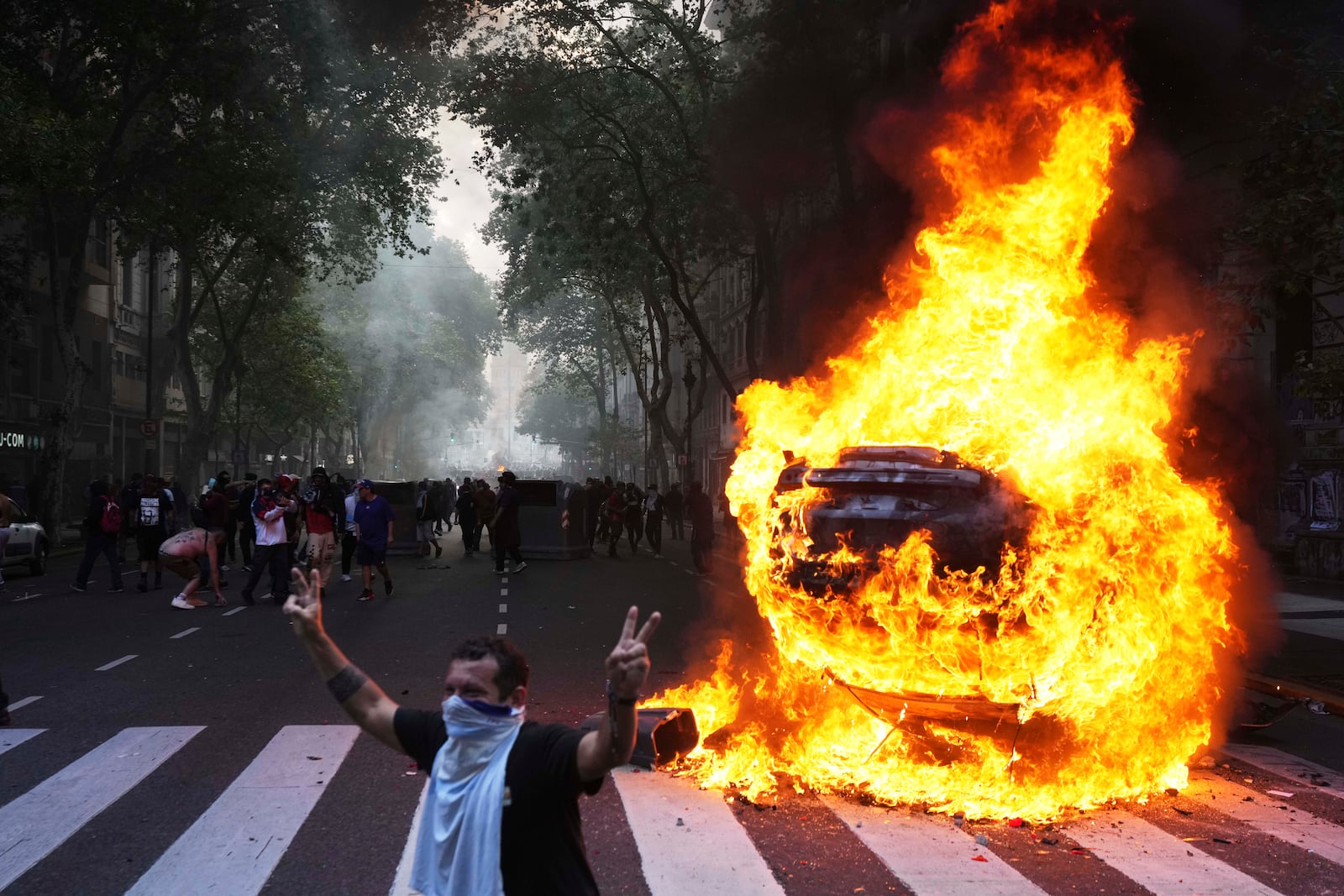 Protesters surround a burning car during a demonstration by soccer fans and retirees demanding higher pensions and opposing austerity measures implemented by Javier Milei's government in Buenos Aires, Argentina, Wednesday, March 12, 2025. (AP Photo/Rodrigo Abd)