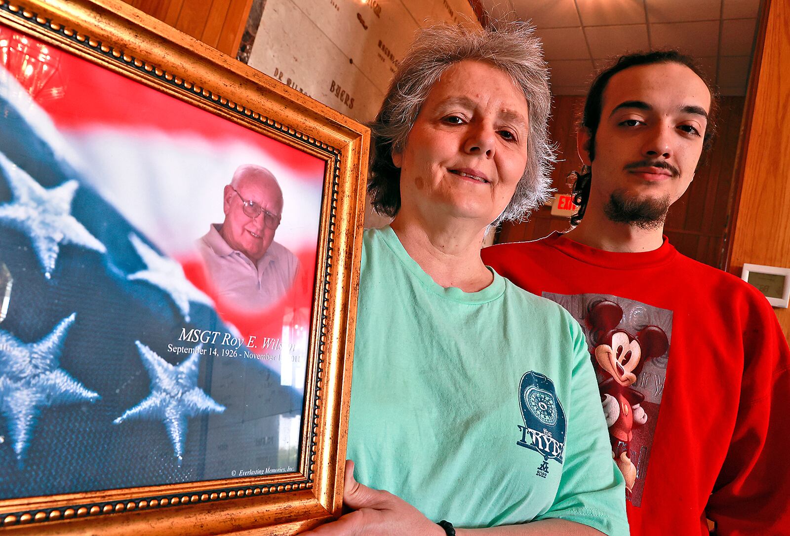 Connie Wilson and her son, Mikey Ziegler, hold a picture of Connie's father, Roy, at Rose Hill Cemetary, where he's buried. BILL LACKEY/STAFF