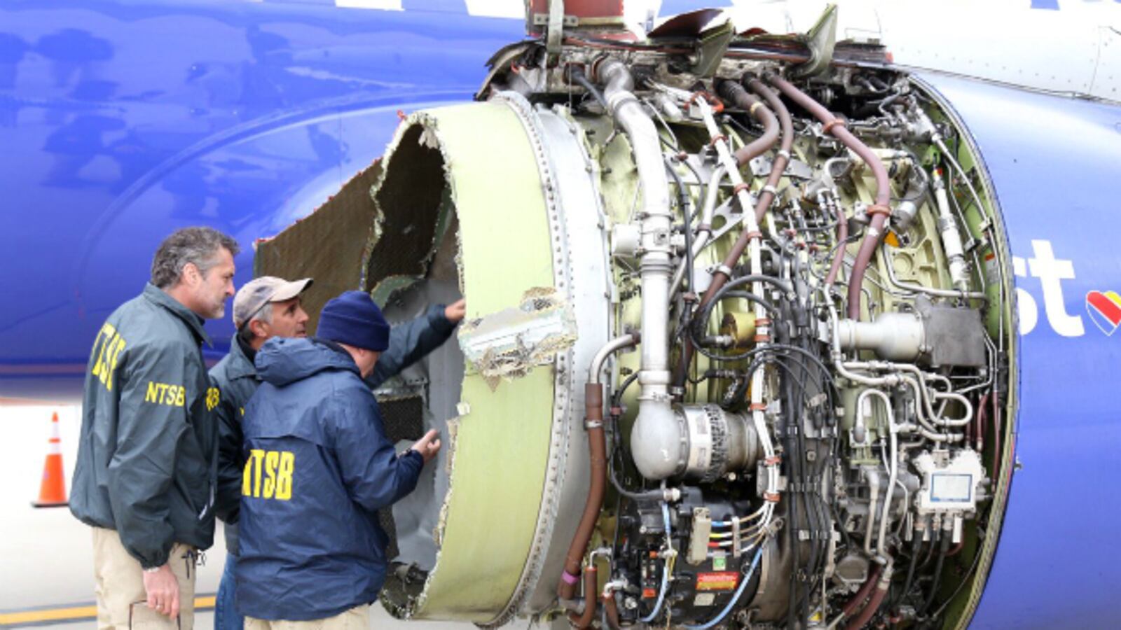 Investigators with the National Transportation Safety Board examine damage to the engine of a Southwest Airlines plane at Philadelphia International Airport on Tuesday, April 17, 2018.