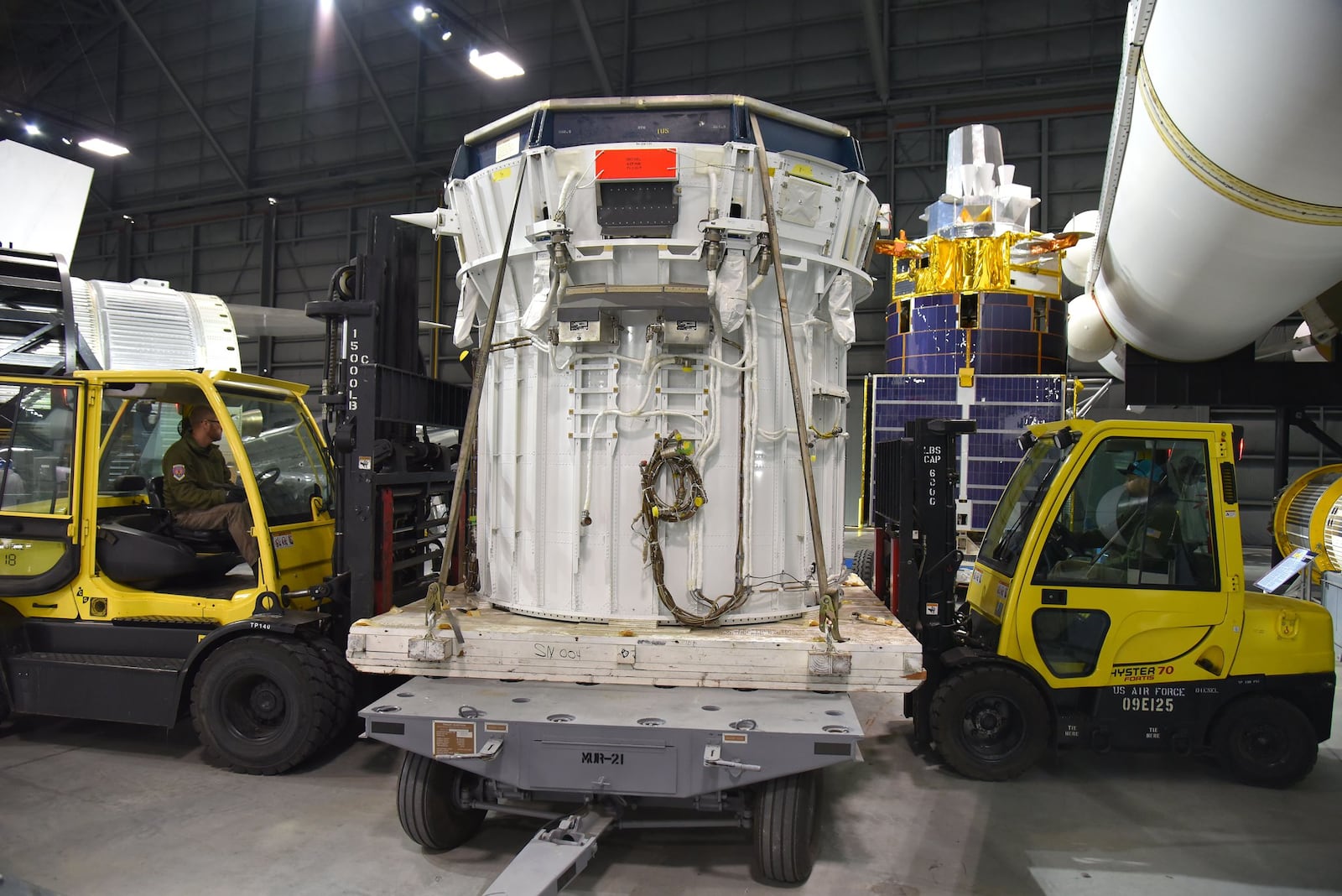 From left, museum restoration specialists Brian Neill and Matt Gideon position stage two of the IUS Upper Stage vehicle. Plans call for the Northrop Grumman Defense Support Program Satellite to be mounted to the IUS on display in the Space Gallery. CONTRIBUTED/U.S. AIR FORCE/KEN LAROCK