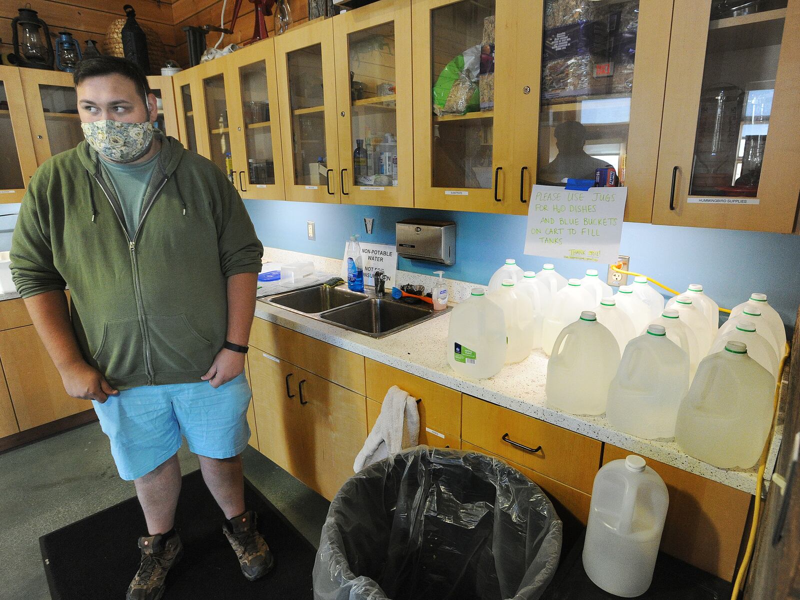 Sean Mormino, environmental education and animal care coordinator at the Aullwood Audubon Farm Discovery Center, stands near jugs the staff uses to transport water for animals after PFAS was discovered  in the facility's drinking water system. MARSHALL GORBY\STAFF