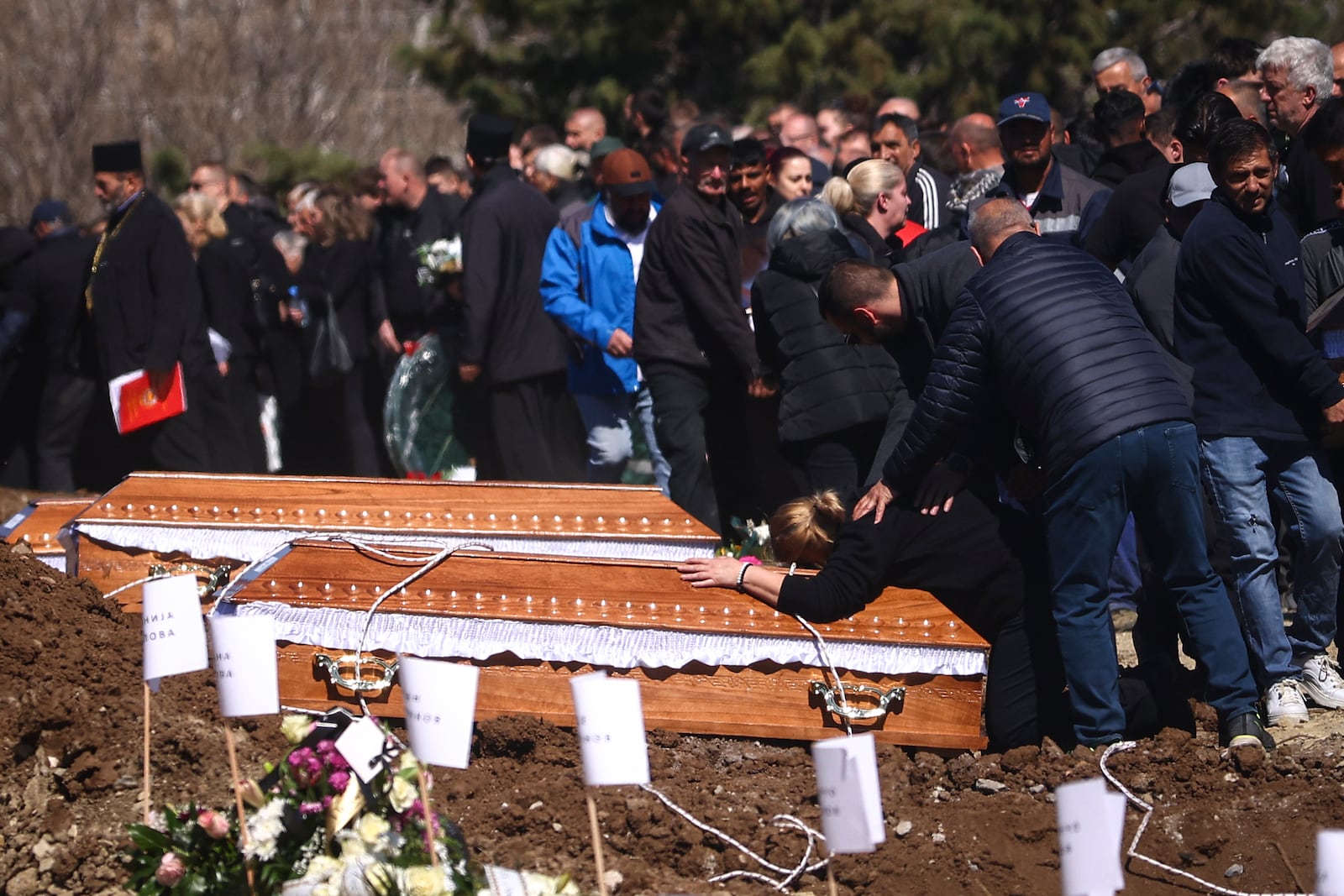 A woman clutches a coffin during the funeral ceremony of the victims of a massive nightclub fire in the town of Kocani, North Macedonia, Thursday, March 20, 2025. (AP Photo/Armin Durgut)