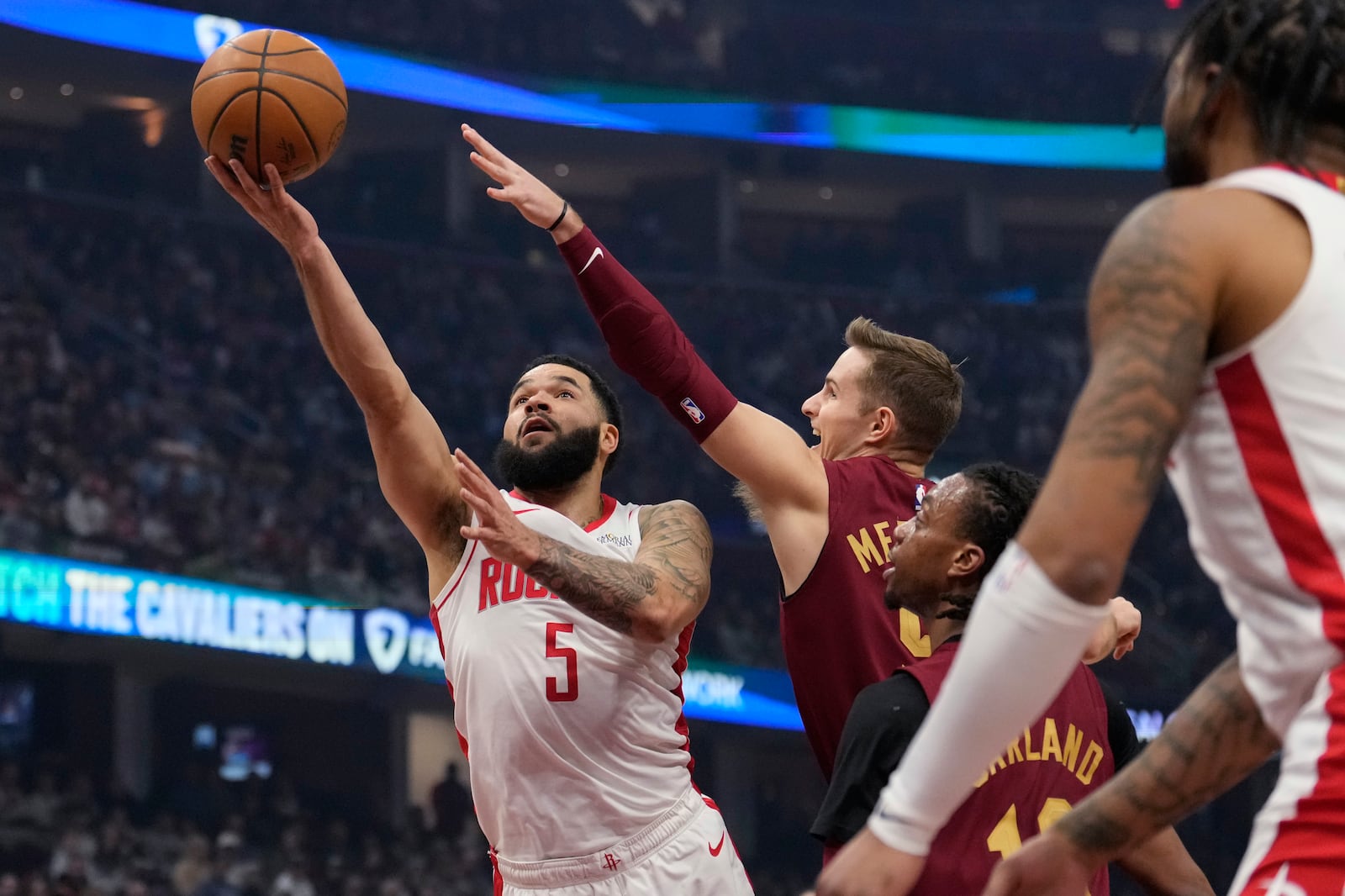 Houston Rockets guard Fred VanVleet (5) shoots defended by Cleveland Cavaliers guard Sam Merrill, center, in the first half of an NBA basketball game, Saturday, Jan. 25, 2025, in Cleveland. (AP Photo/Sue Ogrocki)