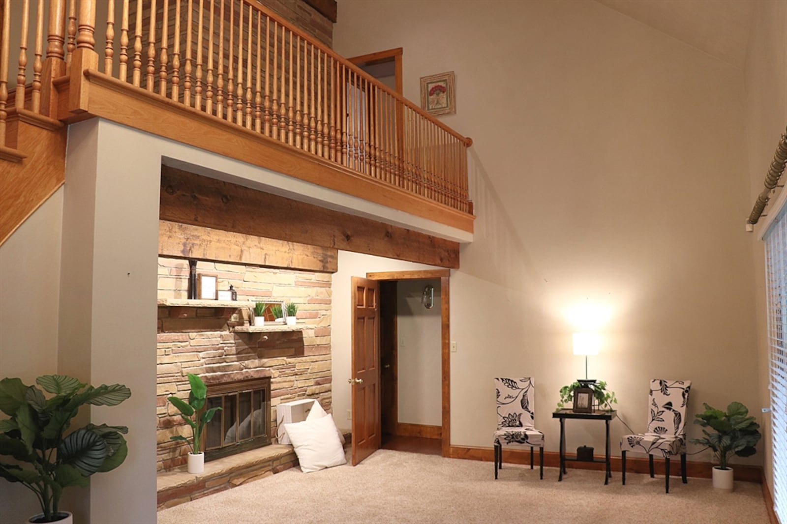 A beautiful curved wooden staircase leads up from the living room to the loft, which is surrounded by a spindled railing. 