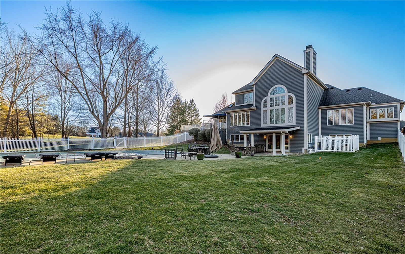 The backyard is partially fenced around the pool area and has mature trees for privacy.