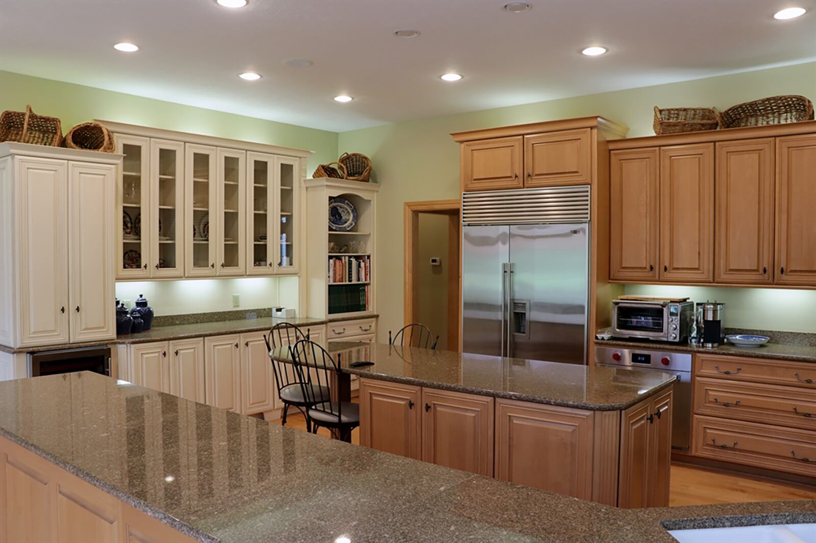 Light cherry cabinetry fills most of the kitchen wall space and includes plate racks and glass-front china cabinets. A corner sink is set into the peninsula and near the gas cooktop with grill and griddle. A wall of antique white cabinetry has spice drawers, a buffet counter, baker’s pantry and coffee station. An island has additional storage and an extended counter for breakfast bar seating for three. CONTRIBUTED PHOTO BY KATHY TYLER