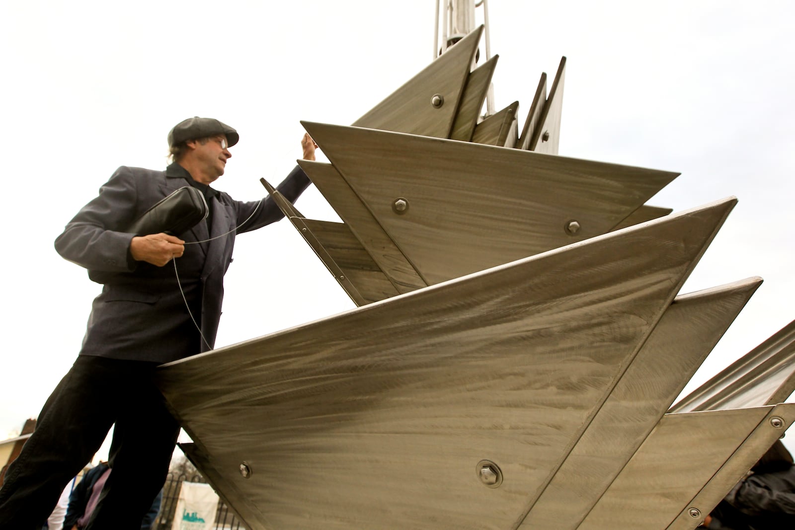 Artist Michael Bashaw adjusts cables on his 26 foot tall sound sculpture that can produce a few bars of Roger Troutman's song "I Can Make You Dance" when moved by the wind. The sculpture, named after the song, was dedicated Tuesday on the site of the former Troutman Sound Labs at the northwest corner of Catalpa Drive and Salem Avenue. Staff photo by Jim Witmer