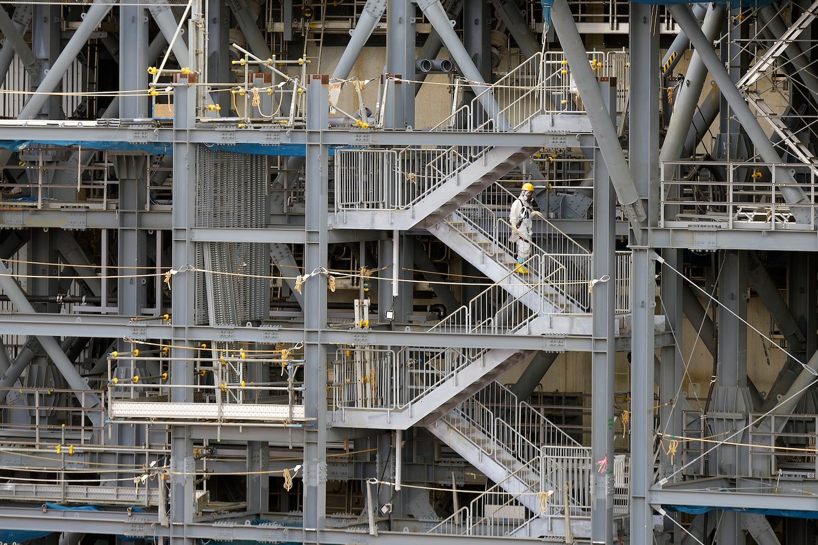 A worker in hazmat suits take stairs at the damaged Unit 1 reactor of the Fukushima Daiichi nuclear power plant, operated by Tokyo Electric Power Company Holdings (TEPCO), in Okuma town, northeastern Japan on Monday Feb. 20, 2025. (AP Photo/Eugene Hoshiko)