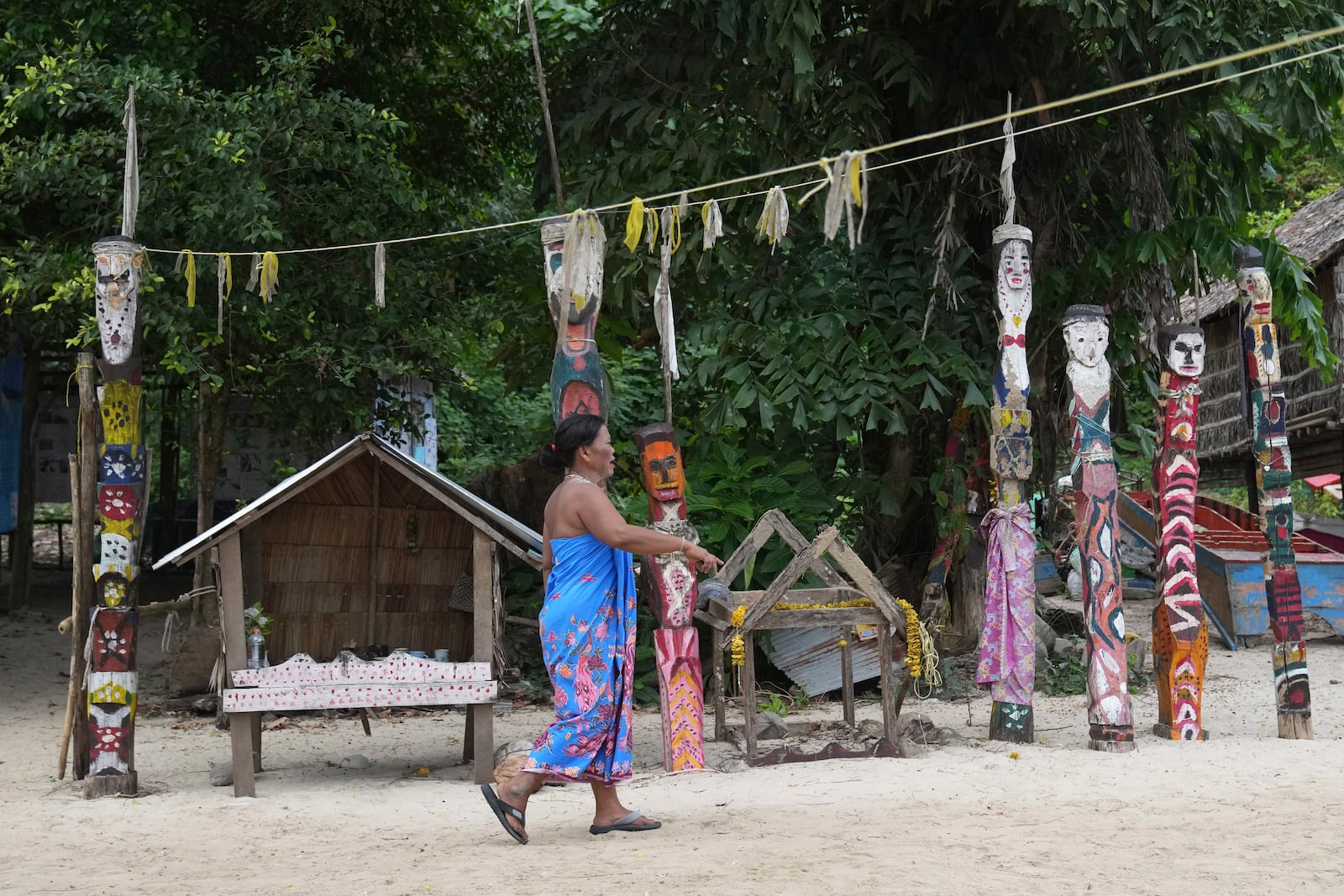 A Moken villager walks in front of spirit poles at Surin Islands in Phang Nga Province, Thailand, Thursday, Dec. 12, 2024. (AP Photo/Sakchai Lalit)