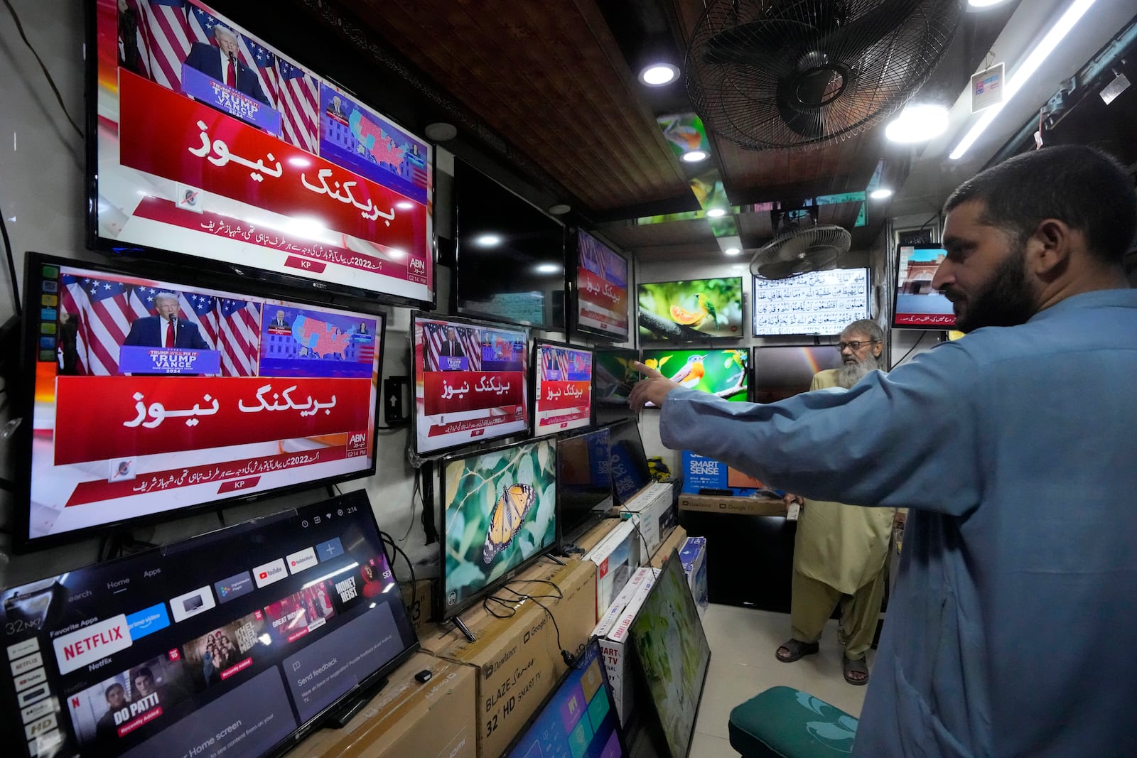 Pakistanis watch news channels broadcasting results of U.S. presidential elections, at a shop in Karachi, Pakistan, Wednesday, Nov. 6, 2024. (AP Photo/Fareed Khan)