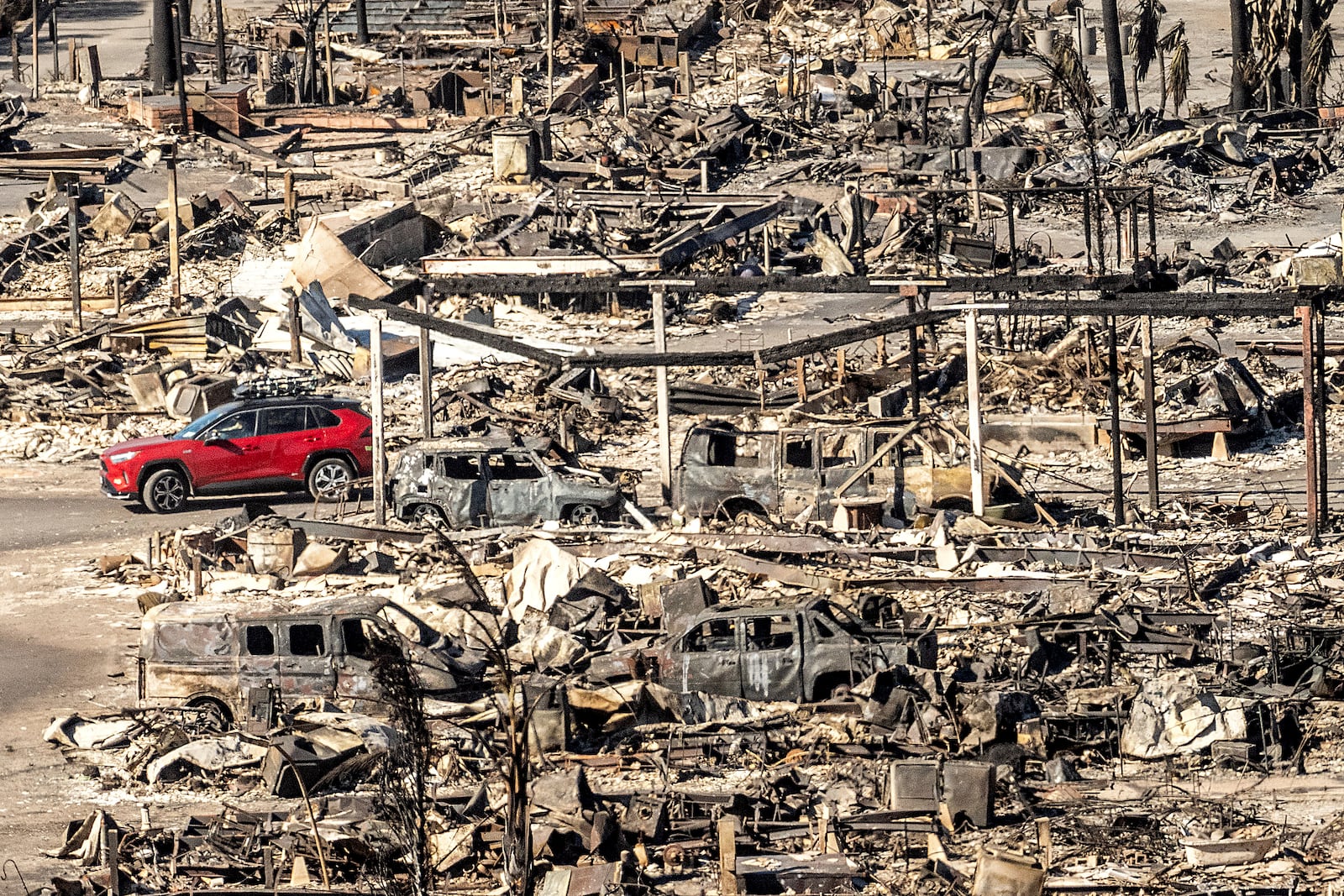 A car drives past homes and vehicles destroyed by the Palisades Fire at the Pacific Palisades Bowl Mobile Estates on Sunday, Jan. 12, 2025, in Los Angeles. (AP Photo/Noah Berger)