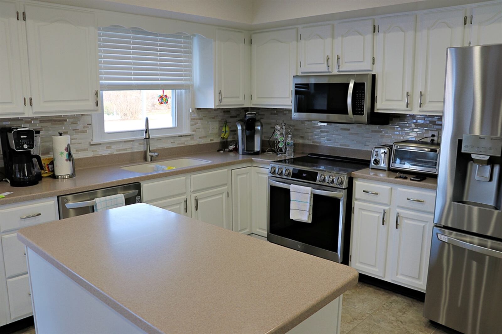 Kitchen was updated with painted cabinetry, solid-surface counters and stainless-steel appliances. The breakfast room has a buffet counter with glass rack and glass-door cabinets.