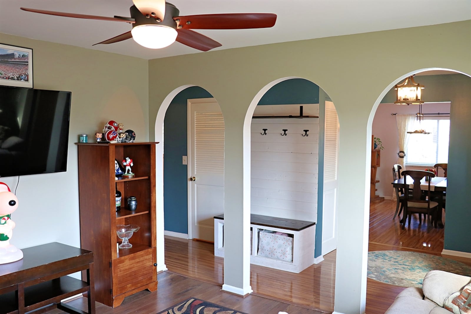 Three arched walkways accent the formal living room, which has a picture window and wood-plank laminated flooring. 