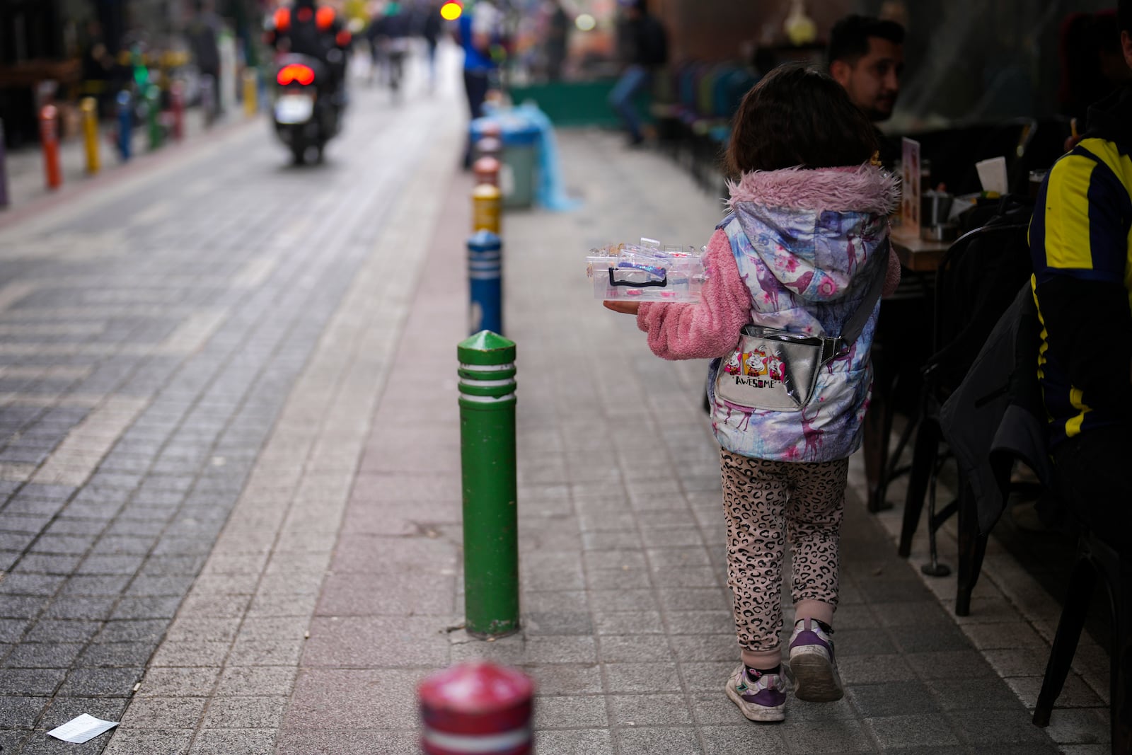 A girl sells plastic items to people in the Kadikoy district in Istanbul, Turkey, Saturday, Dec. 7, 2024. (AP Photo/Francisco Seco)