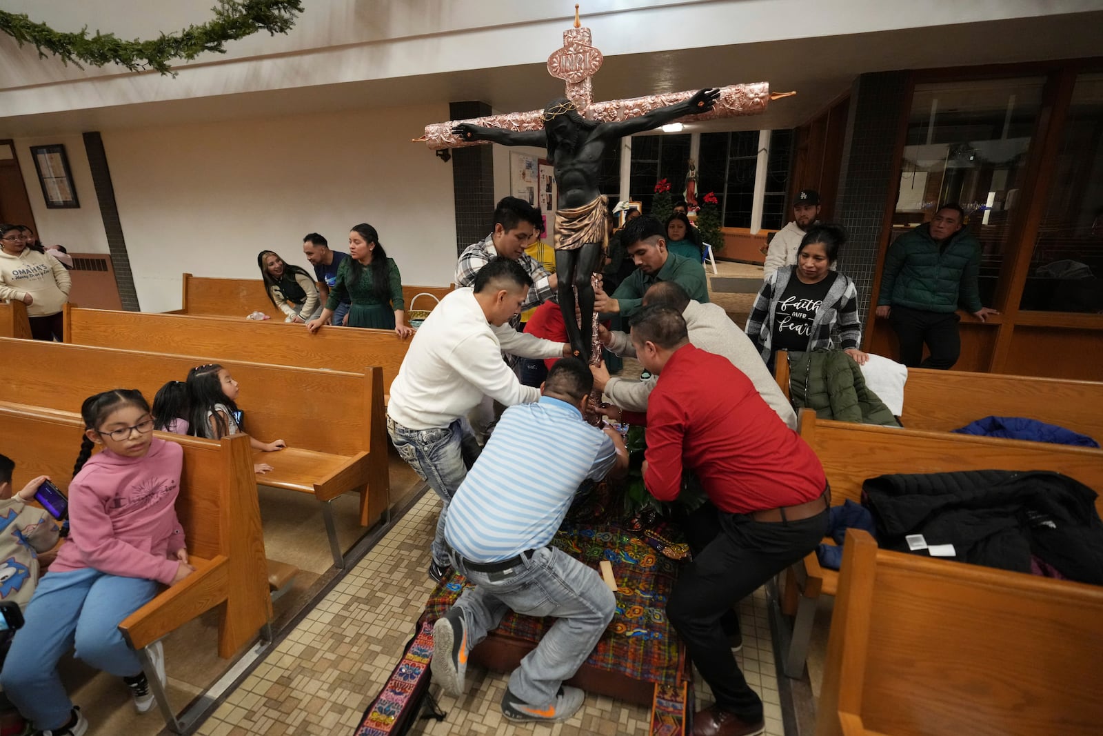 Church members place a replica of Guatemala's Black Christ of Esquipulas statue on a precessional float the day before celebrating its feast day at St. Mary's Catholic Church in Worthington, Minnesota, Saturday, Jan. 11, 2025. (AP Photo/Abbie Parr)