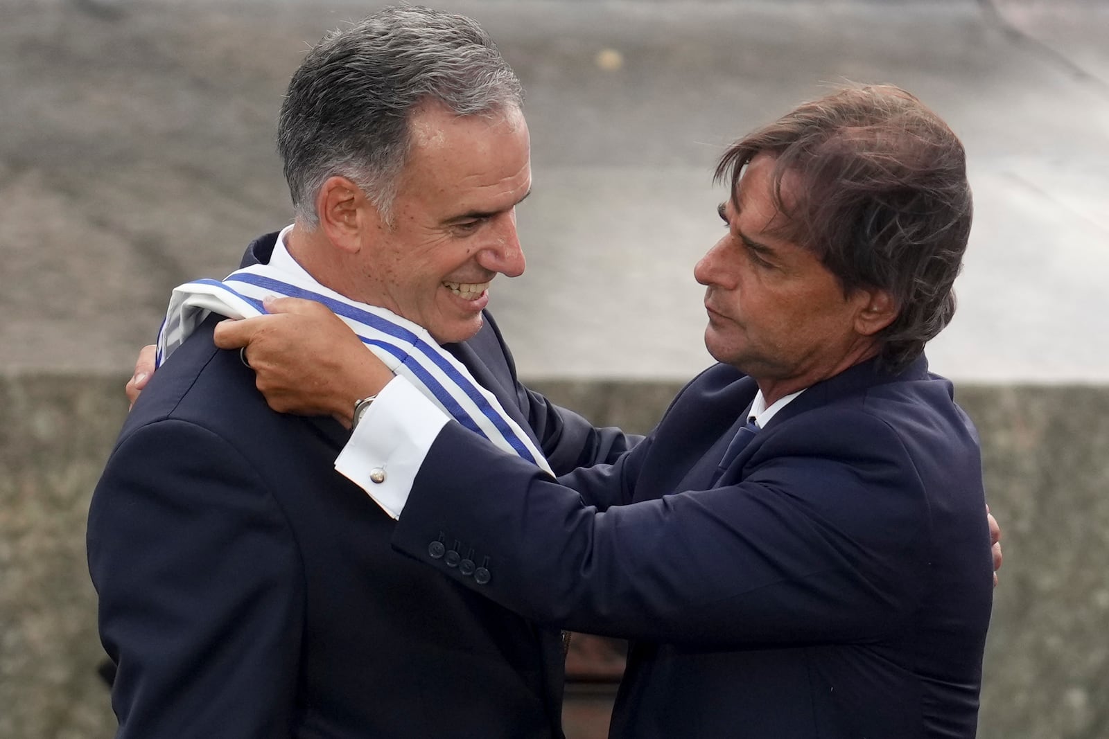 Uruguay's outgoing President Luis Lacalle Pou, right, places the presidential sash on incoming President Yamandu Orsi, on Inauguration Day in Montevideo, Uruguay, Saturday, March 1, 2025. (AP Photo/Matilde Campodonico)