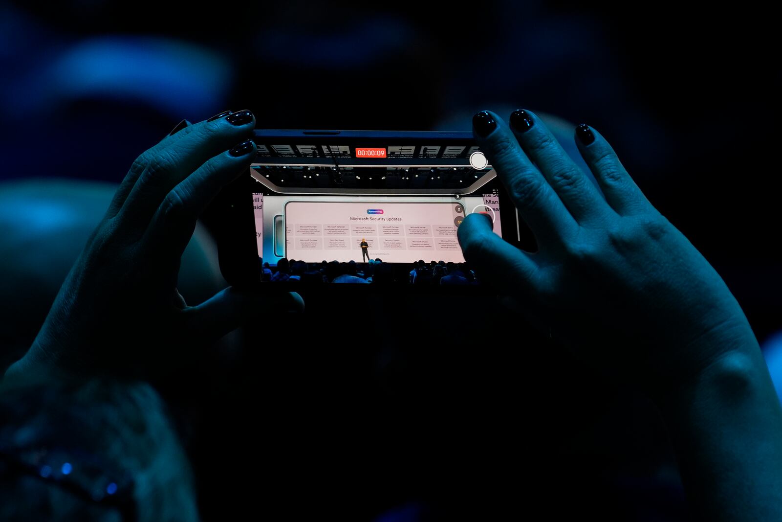 An attendee at the Microsoft Ignite conference records CEO Satya Nadella as he delivers the keynote address at the conference Tuesday, Nov. 19, 2024, in Chicago. (AP Photo/Charles Rex Arbogast)