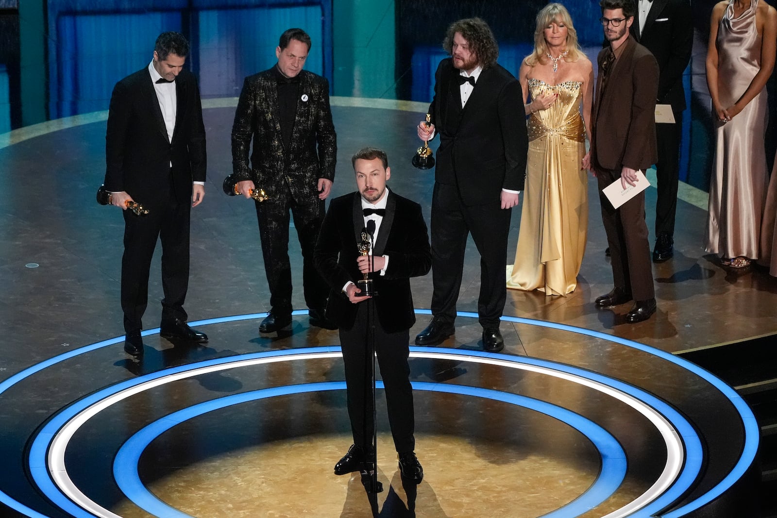 Gregory Zalcman, from left, Ron Dyens, Gints Zilbalodis, center, and Matiss Kaza accept the award for best animated feature film for "Flow" during the Oscars on Sunday, March 2, 2025, at the Dolby Theatre in Los Angeles. Goldie Hawn, second right, and Andrew Garfield look on from right. (AP Photo/Chris Pizzello)