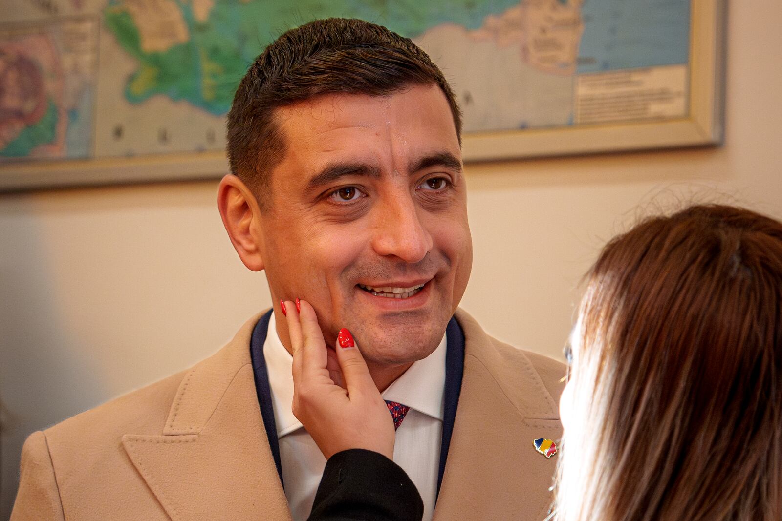 George Simion, the Alliance for the Unity of Romanians (AUR) candidate for president, smiles as his wife Ilinca caresses his face before casting her vote at a voting station during the country's presidential elections, in Bucharest, Romania, Sunday, Nov. 24, 2024. (AP Photo/Andreea Alexandru)