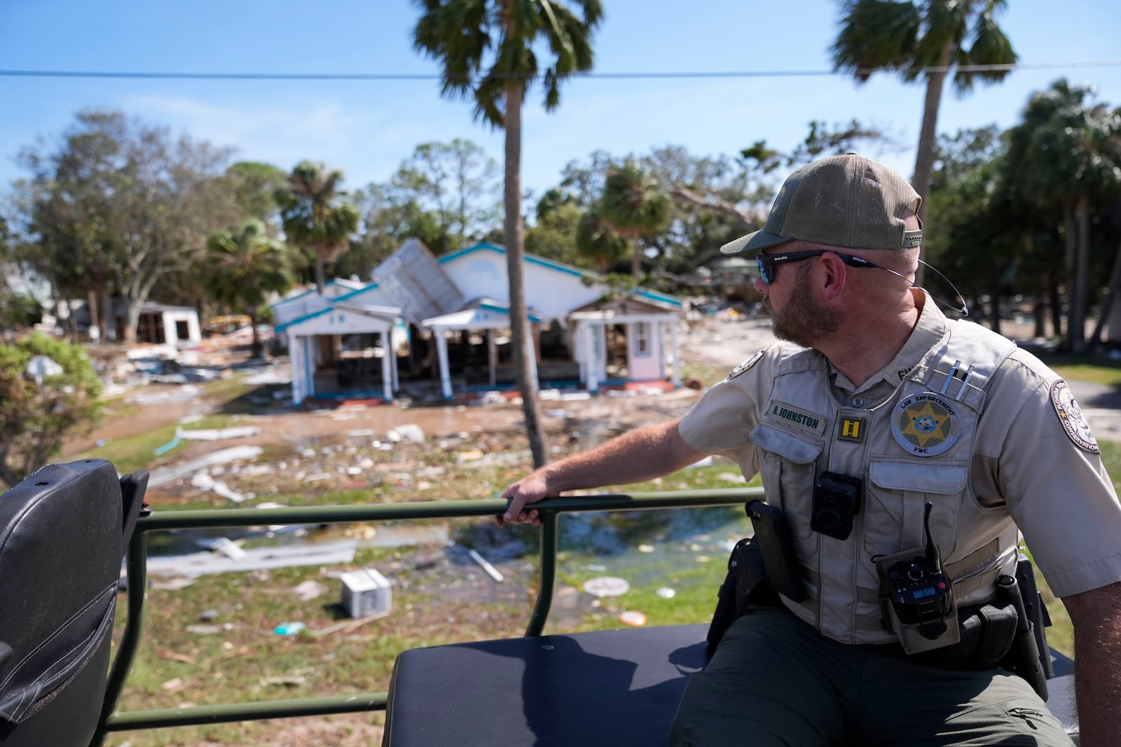 Capt. BJ Johnston, a law enforcement officer from the Florida Fish Wildlife and Conservation Commission surveys destruction from a high water buggy in the aftermath of Hurricane Helene, in Cedar Key, Fla., Friday, Sept. 27, 2024. (AP Photo/Gerald Herbert)