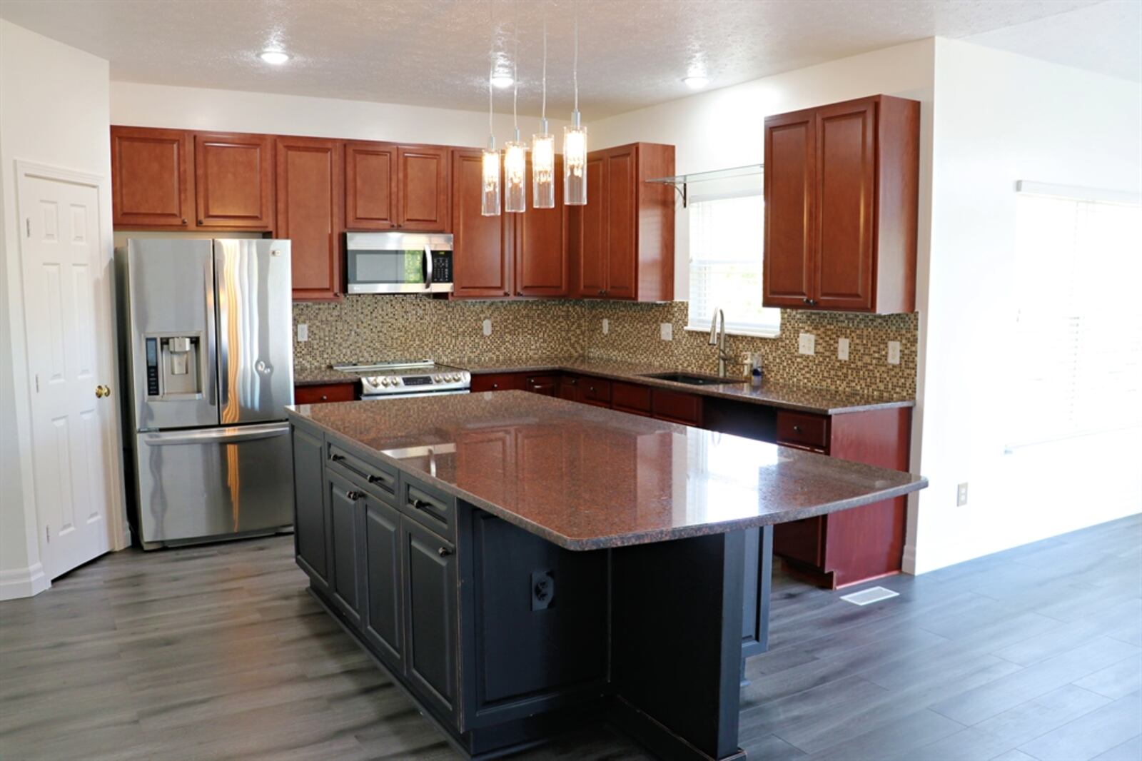 In the kitchen, mosaic tile creates a backsplash and lighting is available under cabinets and above the island.