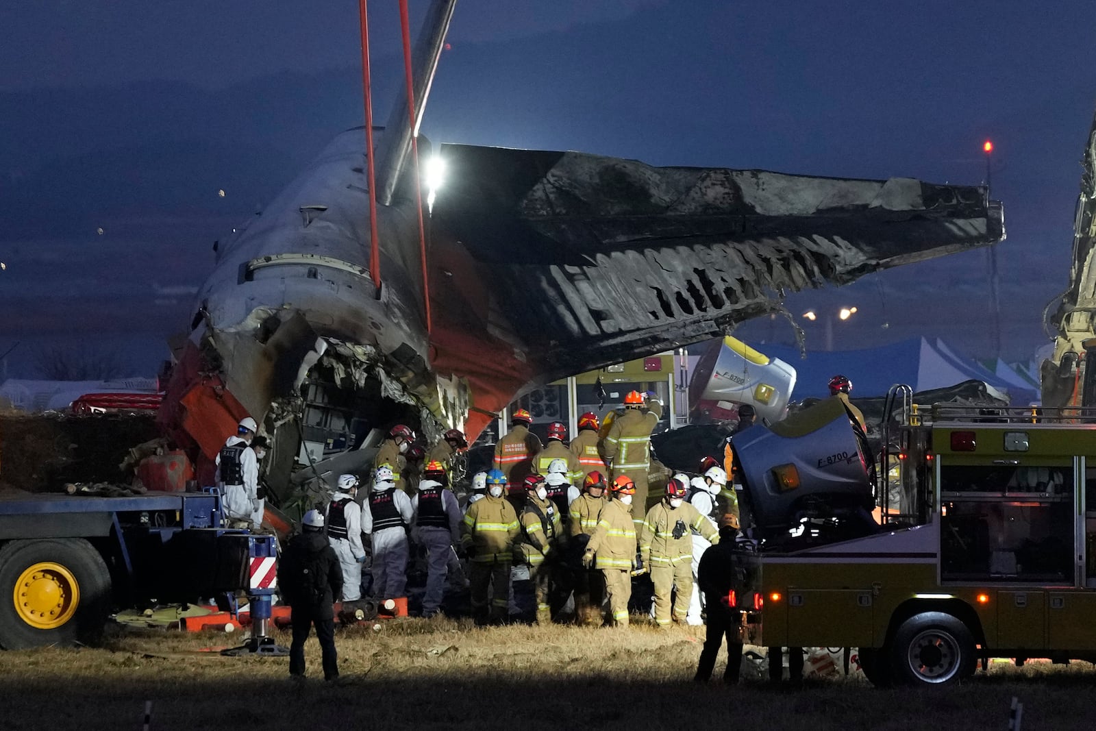 Rescue team carry the body of a passenger at the site of a plane fire at Muan International Airport in Muan, South Korea, Sunday, Dec. 29, 2024. (AP Photo/Ahn Young-joon)