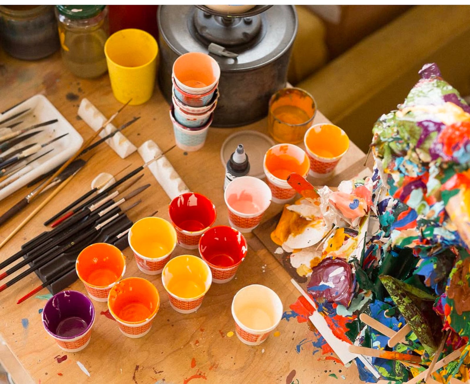 Paints in the Ink & Hammer studio with an improvised sculpture of dried out enamel skins from the tops of paint cans.