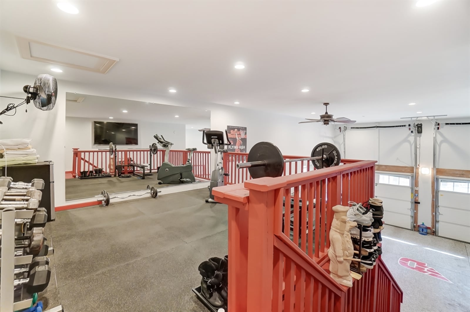 Access to the three-car garage opens into a loft fitness deck with rail surround, rubber floor and fans.