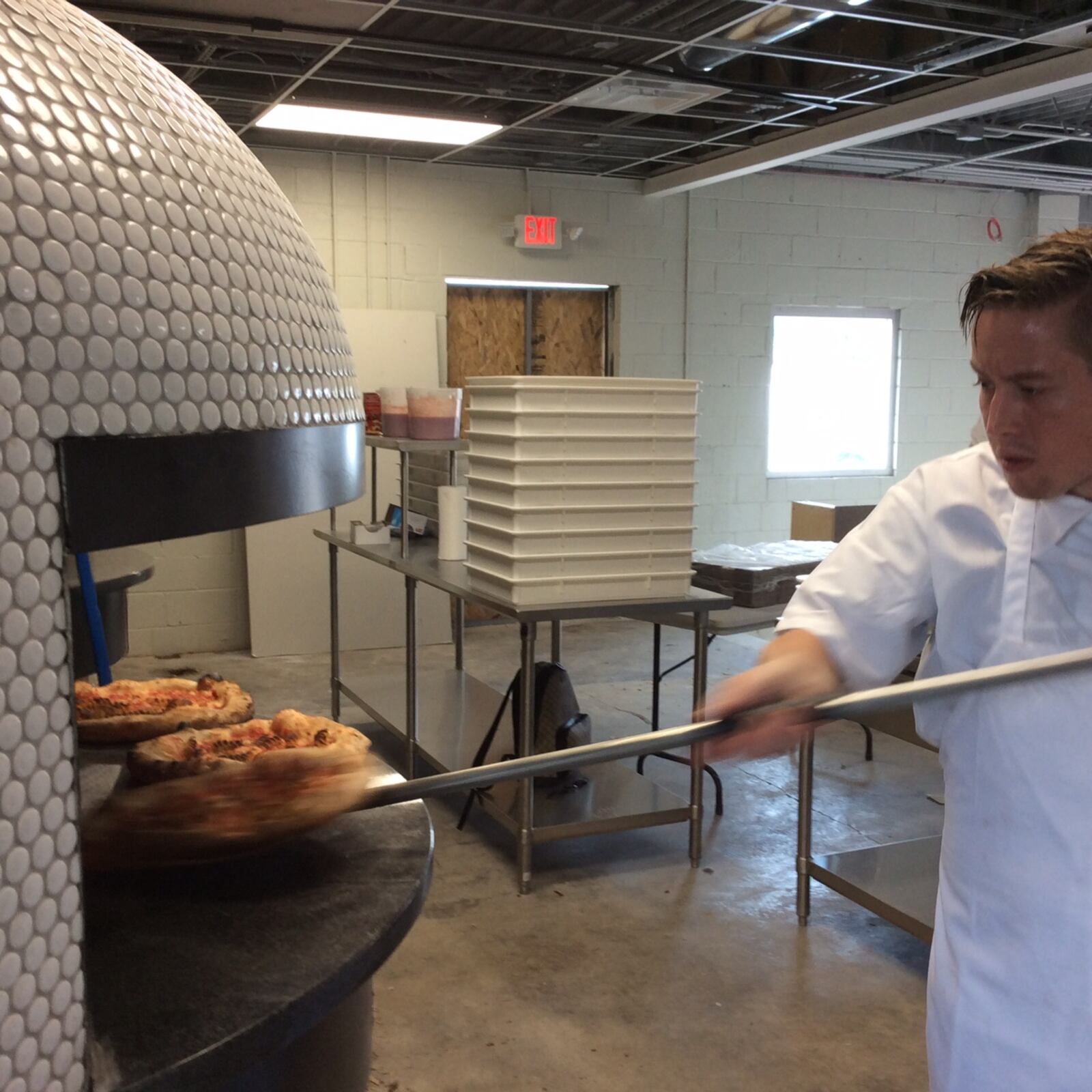 Kitchen manager Nate Vance removes a test pizza from the ovens at Old Scratch Pizza on Patterson Boulevard in Dayton. The restaurant is projected to open in October. MARK FISHER/STAFF