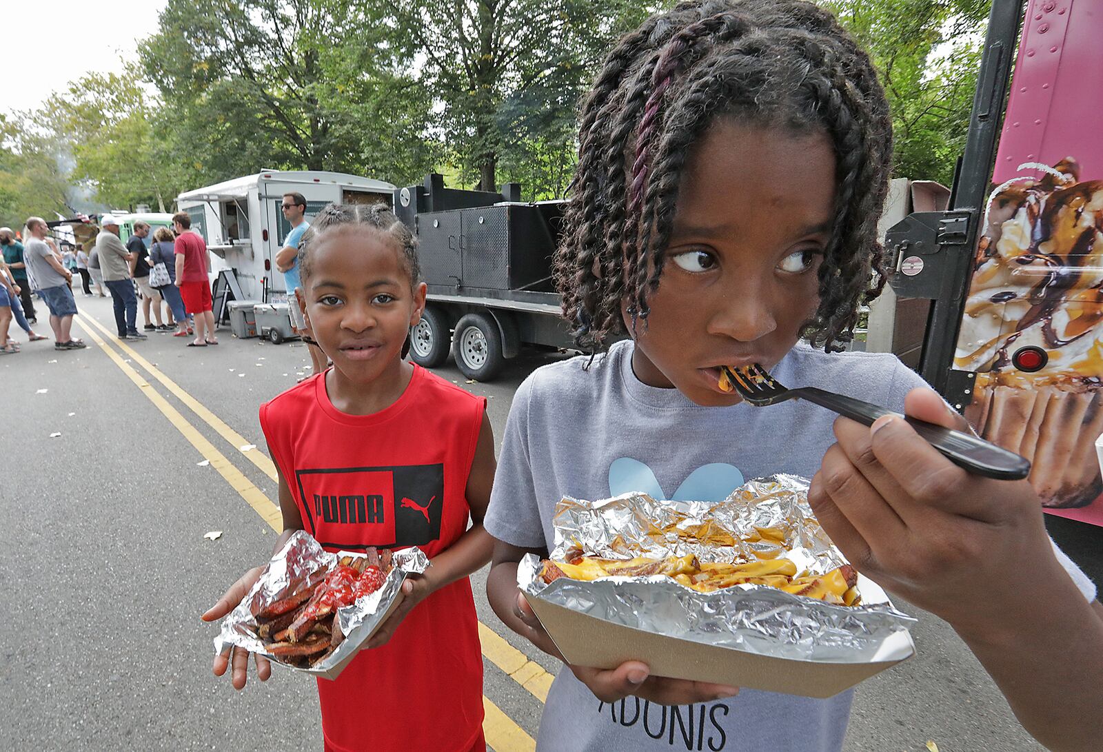 Arenzo Ross, left, and Adonis Rhodes enjoy their gournet french fries Saturday at the Springfield Rotary Gourmet Food Truck Competition in Veteran's Park. BILL LACKEY/STAFF