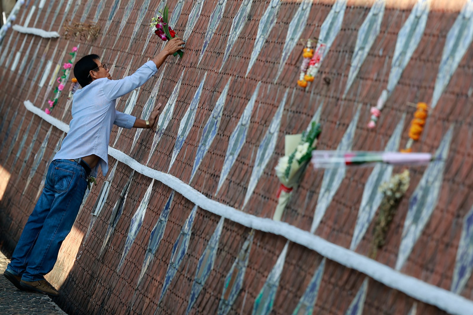 A relative of a victim of a 2004 Indian Ocean tsunami offers flowers during its 20th anniversary at Tsunami Memorial Park at Ban Nam Khem, Takuapa district of Phang Nga province, southern Thailand, Thursday, Dec. 26, 2024. (AP Photo/Wason Wanichakorn)