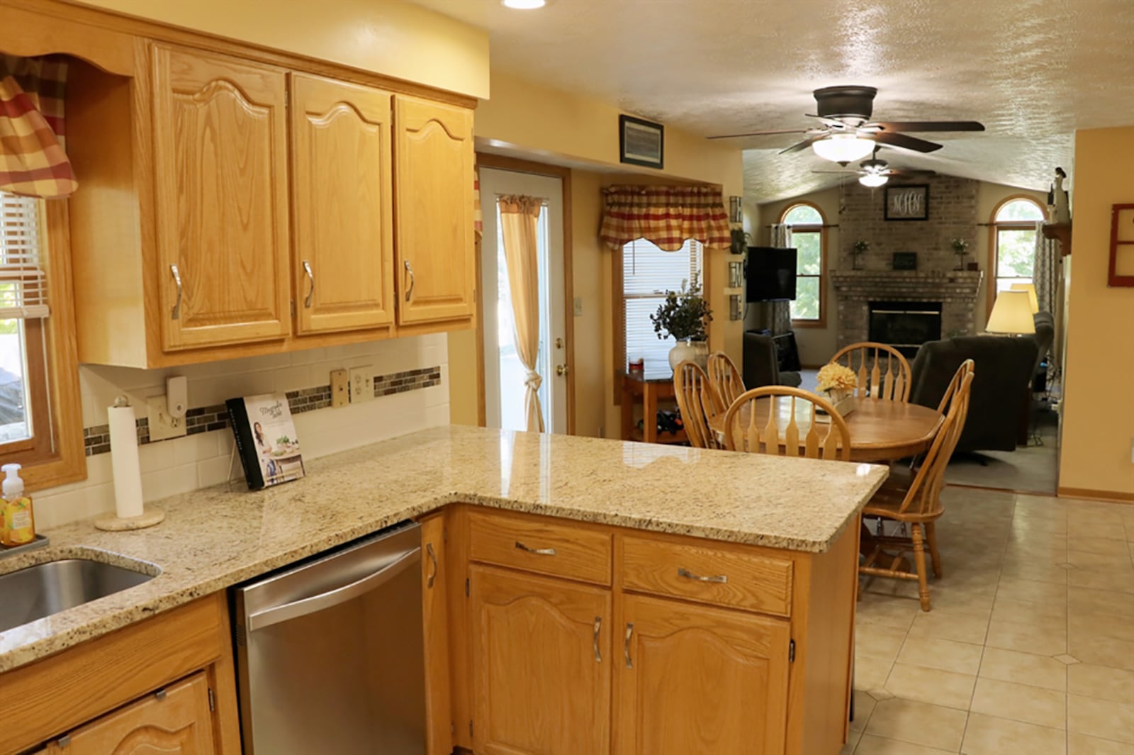 The updated kitchen features oak cabinetry complemented by granite countertops. A single sink is below a window, and a peninsula counter offers breakfast bar seating for three. A bay bump-out allows for a breakfast room setting and transitions from the kitchen into the family room. CONTRIBUTED PHOTO BY KATHY TYLER