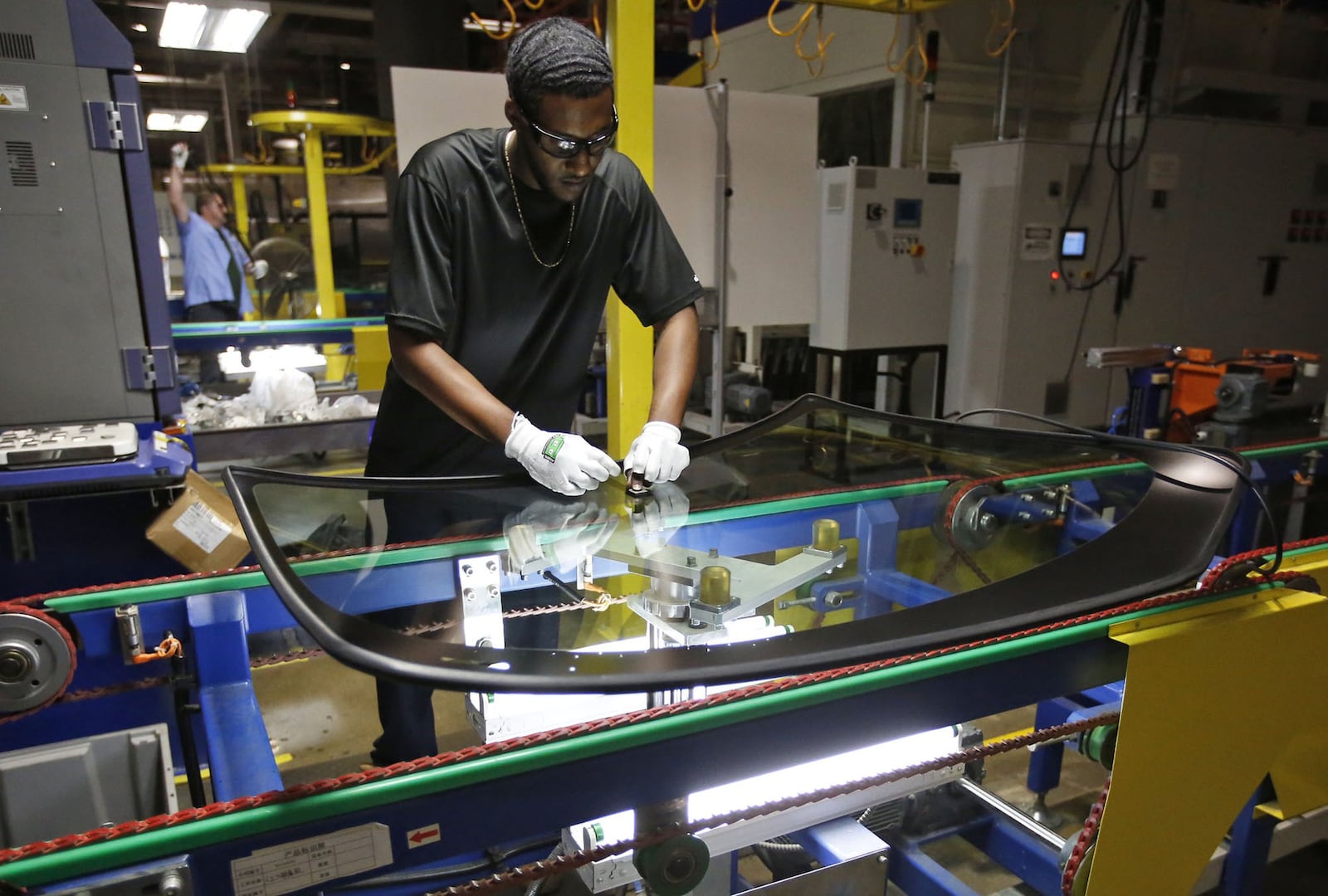 Fuyao Glass America has progressed at a pace that is years ahead of its original schedule and now employs more than 2,000 people. Employees are meticulous about the quality of the glass.  Jarrod Givens aligns hardware to a windshield before it is pressed into place.  TY GREENLEES / STAFF