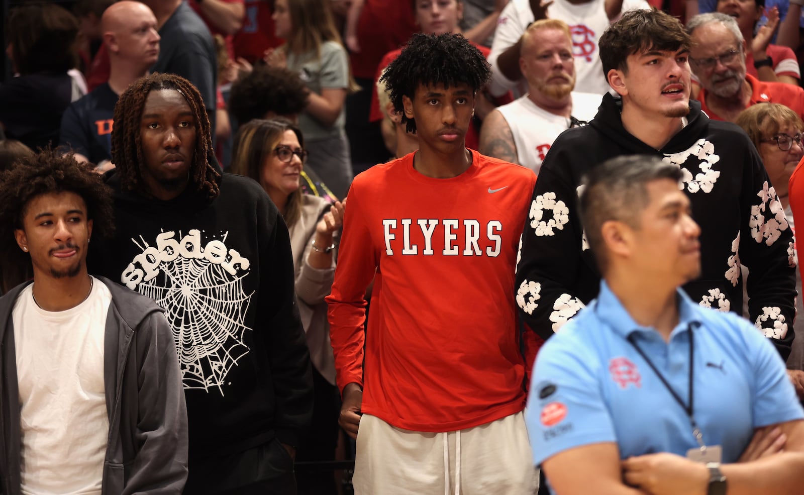 Dayton players watch the Red Scare play DaGuys STL in the first round of The Basketball Tournament on Saturday, July 20, 2024, at UD Arena. Pictured, left to right, are: Javon Bennett; Jaiun Simon; Hamad Mousa; and Isaac Jack. David Jablonski/Staff