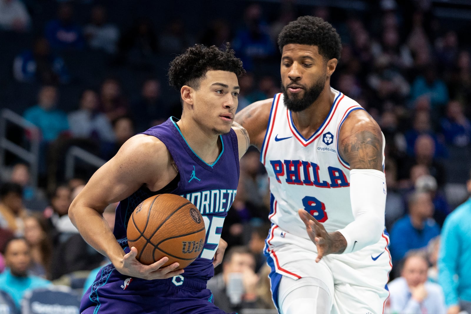 Charlotte Hornets guard KJ Simpson, left, drives against Philadelphia 76ers forward Paul George during the first half of an NBA Cup basketball game in Charlotte, N.C., Tuesday, Dec. 3, 2024. (AP Photo/Nell Redmond)