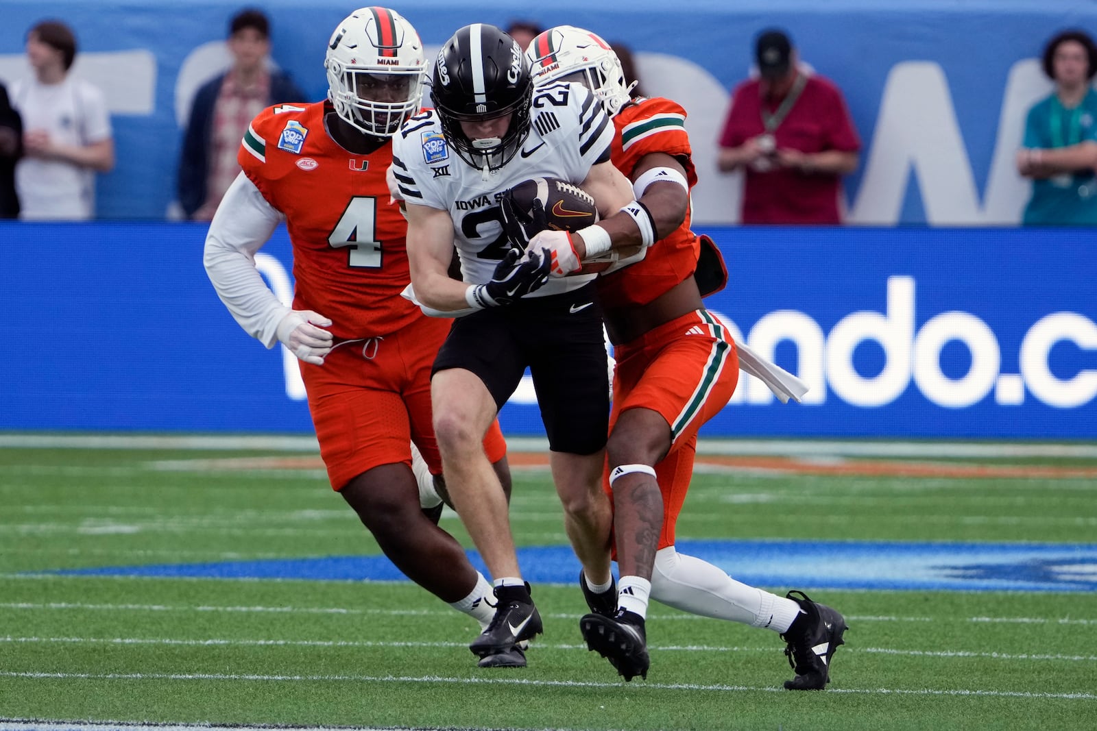 Iowa State wide receiver Eli Green, center, runs after a reception before he is tackled by Miami defensive lineman Rueben Bain Jr. (4) and linebacker Cam Pruitt, right, during the first half of the Pop Tarts Bowl NCAA college football game, Saturday, Dec. 28, 2024, in Orlando, Fla. (AP Photo/John Raoux)