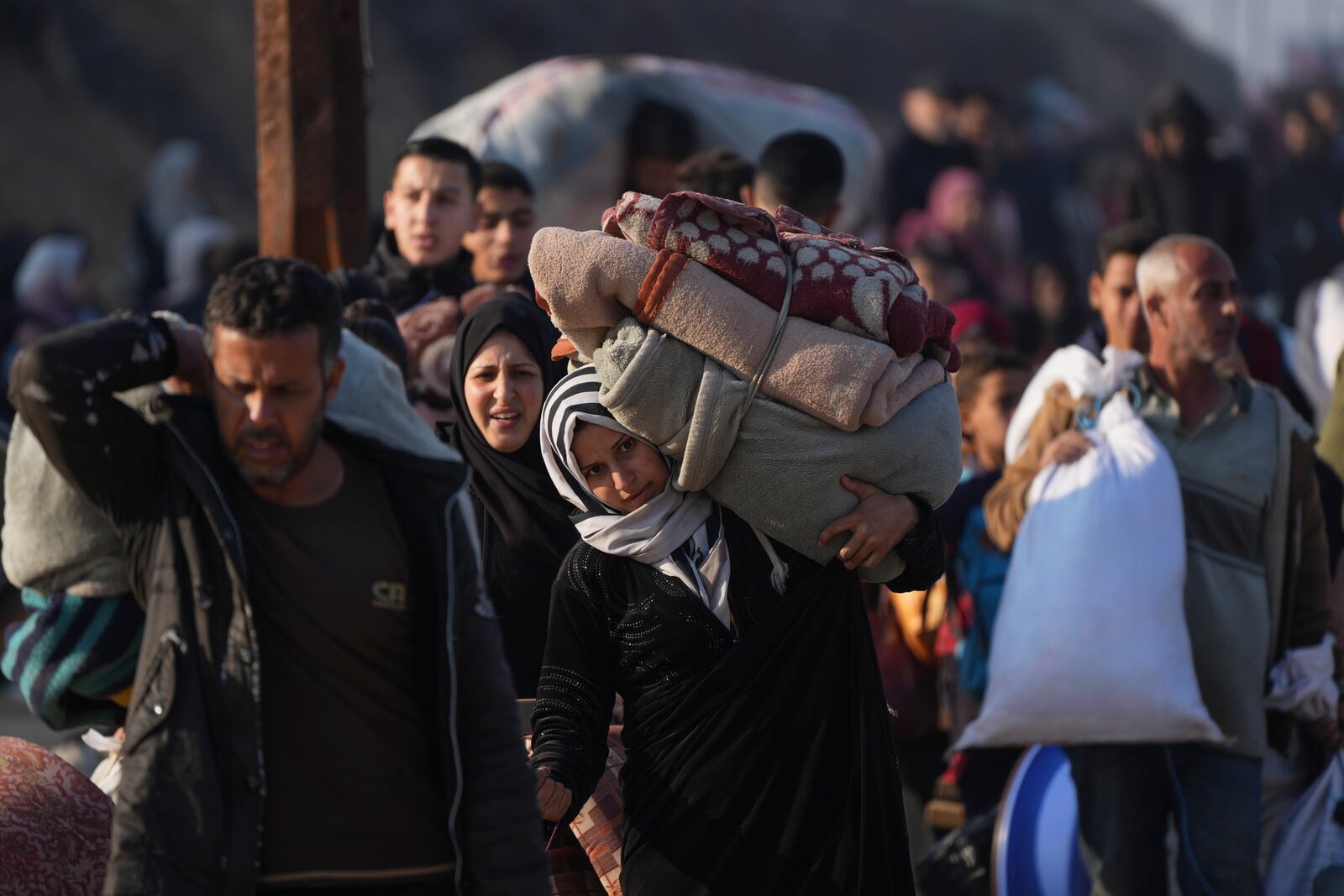 A Palestinian woman carries her belongings as she walks on a road to return to her home in the northern Gaza Strip, Tuesday, Jan. 28, 2025, after Israel's decision to allow thousands of them to go back for the first time since the early weeks of the 15-month war with Hamas. (AP Photo/Abdel Kareem Hana)