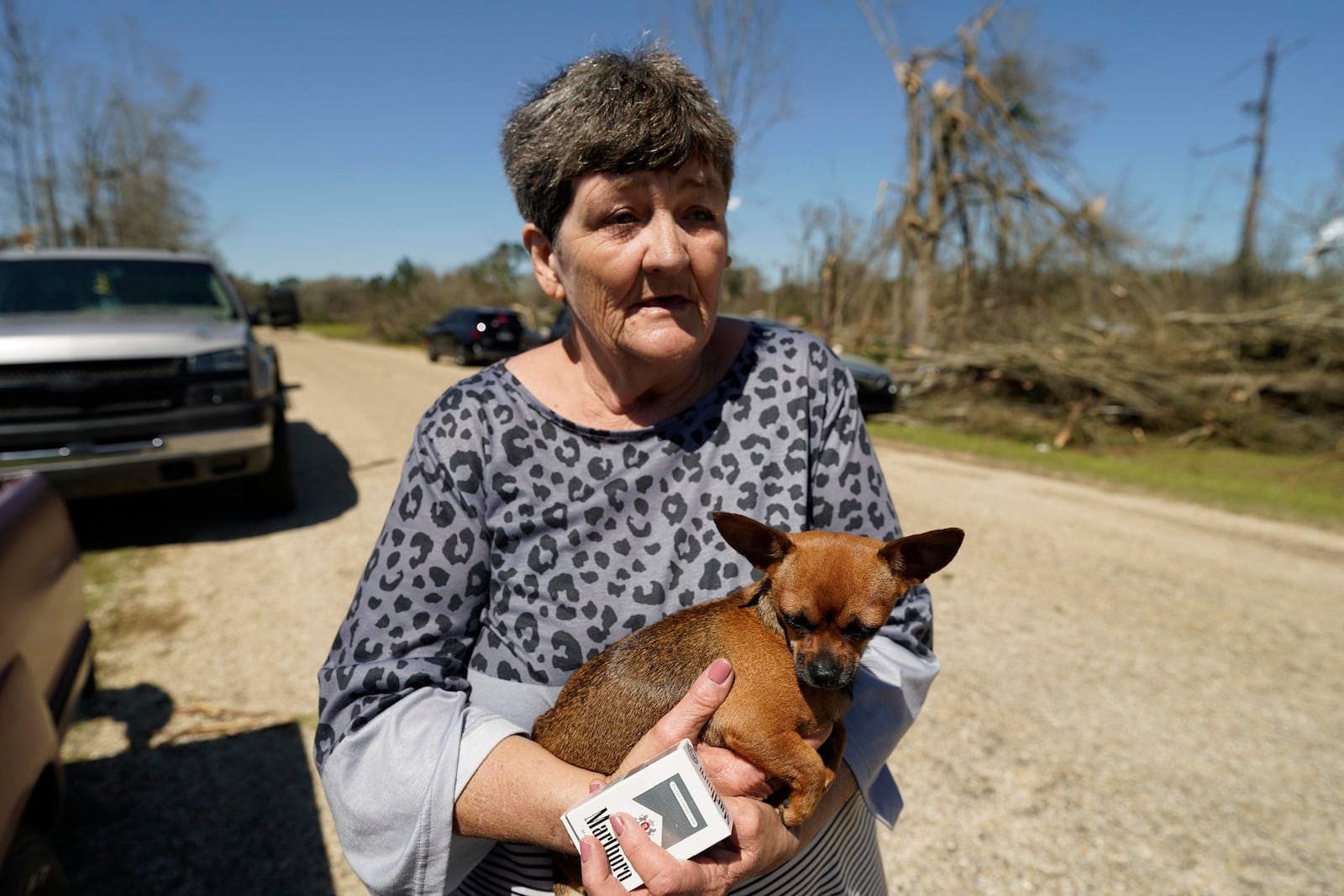 Donna Blansett, holds her dog LuLu, and recalls how she and husband Bobby Blansett, managed to escape Saturday from their tornado destroyed mobile home after a series of storms passed Tylertown, Miss., on Sunday, March 16, 2025. (AP Photo/Rogelio V. Solis)