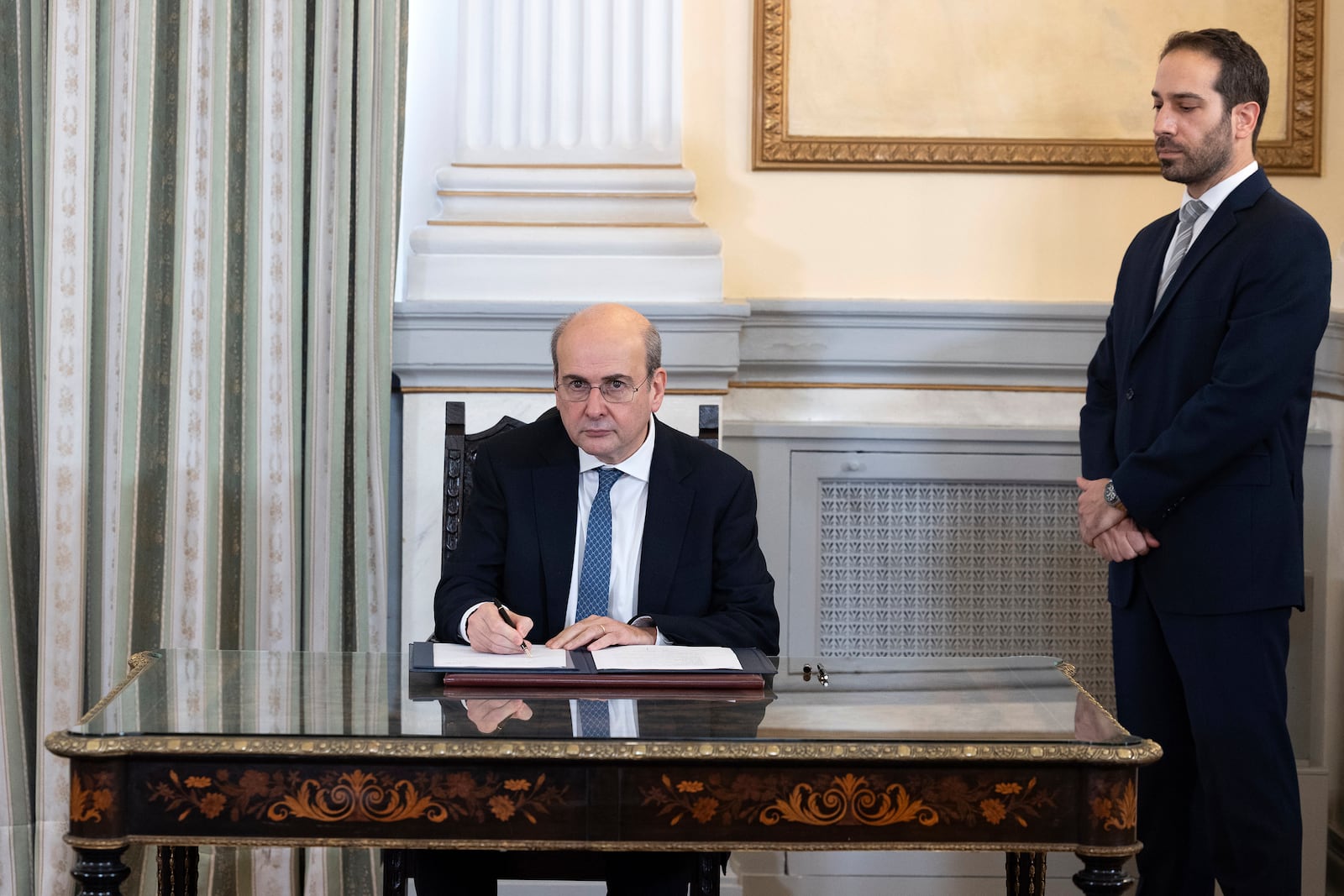 Greece's newly appointed deputy Prime Minister Kostis Hatzidakis signs a document following a swearing in ceremony at the Presidential palace, in Athens, Greece, Saturday, March 15, 2025. (AP Photo/Yorgos Karahalis)