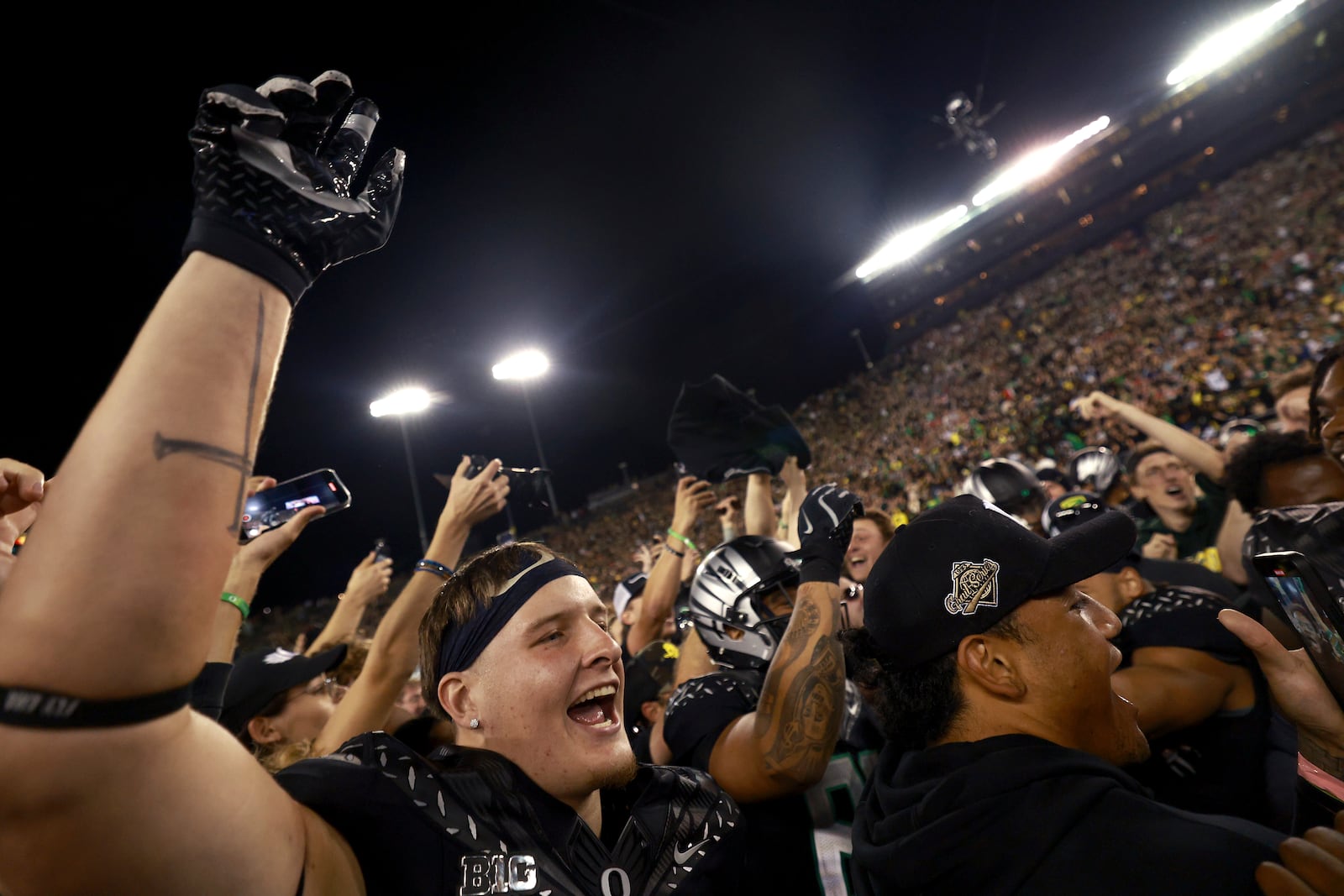 Oregon tight end Kade Caton, left, and fans celebrate on the field after winning an NCAA college football game against Ohio State, Saturday, Oct. 12, 2024, at Autzen Stadium in Eugene, Ore. (AP Photo/Lydia Ely)