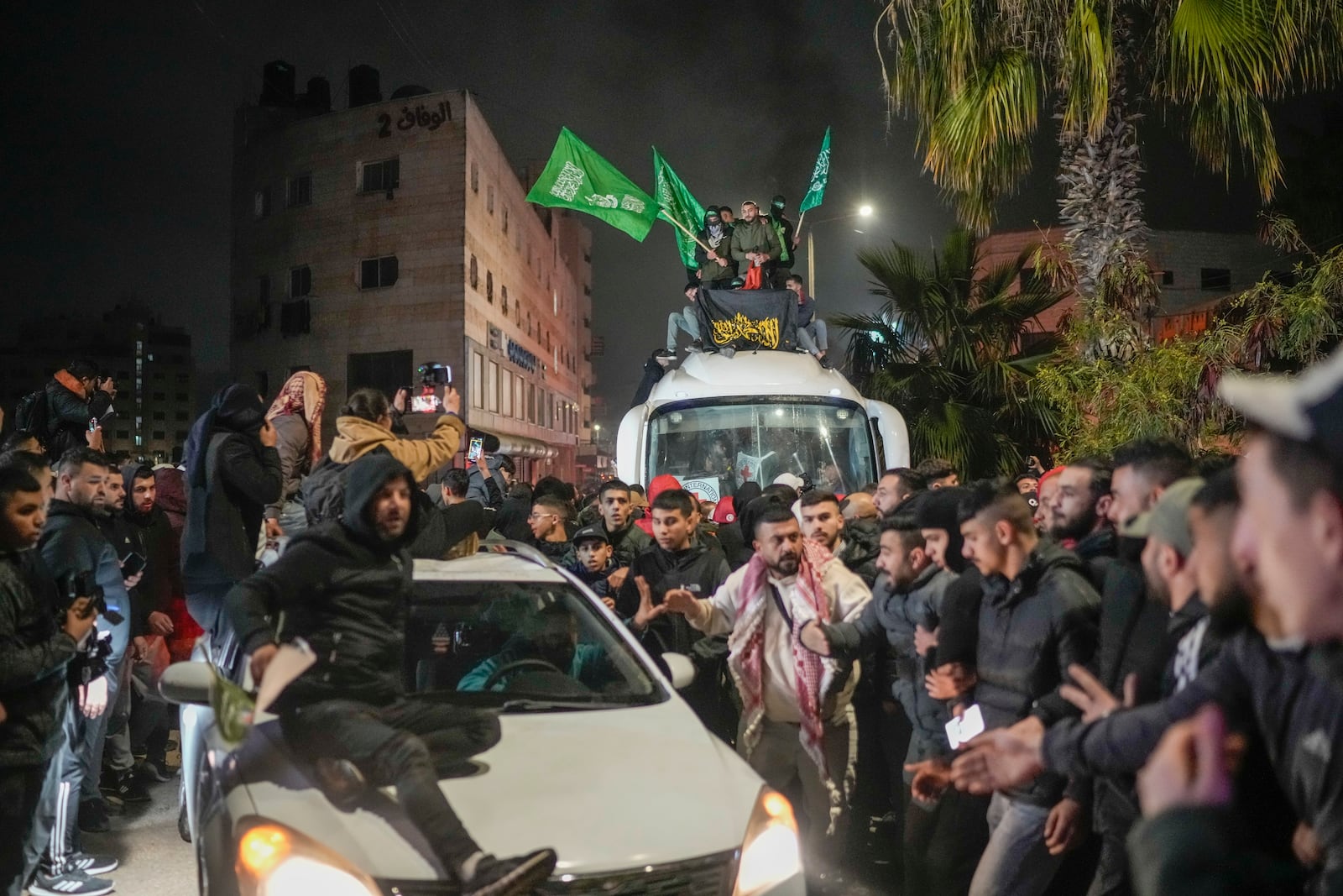 A crowd gathers around a bus carrying released Palestinian prisoners as it arrives in the West Bank city of Beitunia, early Monday, Jan. 20, 2025. (AP Photo/Leo Correa)