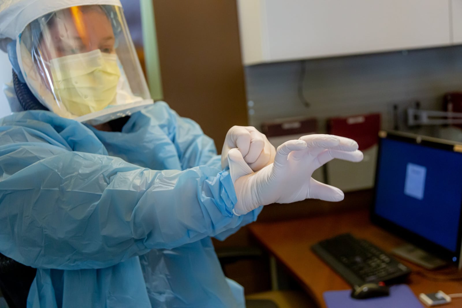 Miami Valley Hospital  respiratory therapist Liz Gilmore dons personal protective equipment, preparing to go into the room of a patient who is positive for COVID-19.