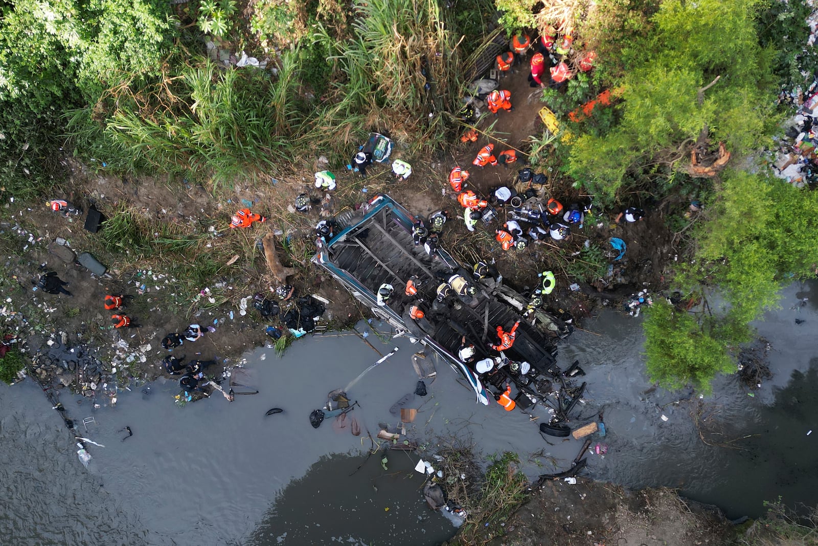 Firefighters work the scene of a fatal bus crash after it fell from a bridge on the outskirts of Guatemala City, Monday, Feb. 10, 2025. (AP Photo/Moises Castillo)