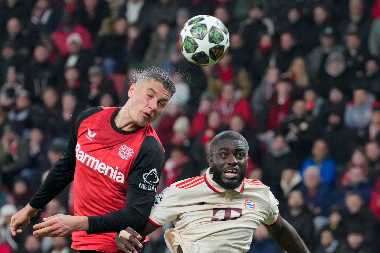 Leverkusen's Patrik Schick, left, jumps for the ball with Bayern's Dayot Upamecano during the Champions League round of 16 second leg soccer match between Bayer Leverkusen and Bayern Munich at the BayArena in Leverkusen, Germany, Tuesday, March 11, 2025. (AP Photo/Martin Meissner)