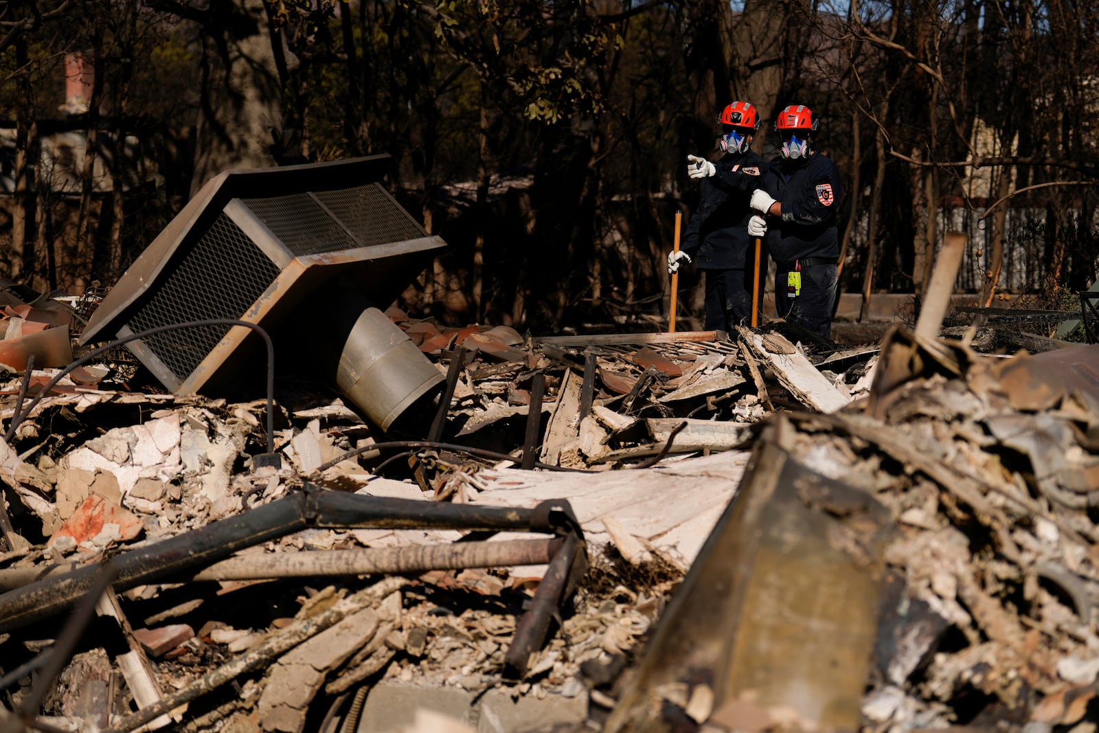 Members of a San Bernardino County Fire Department Search and Rescue crew work among the ruins of the Palisades Fire in the Pacific Palisades neighborhood of Los Angeles, Tuesday, Jan. 14, 2025. (AP Photo/Carolyn Kaster)