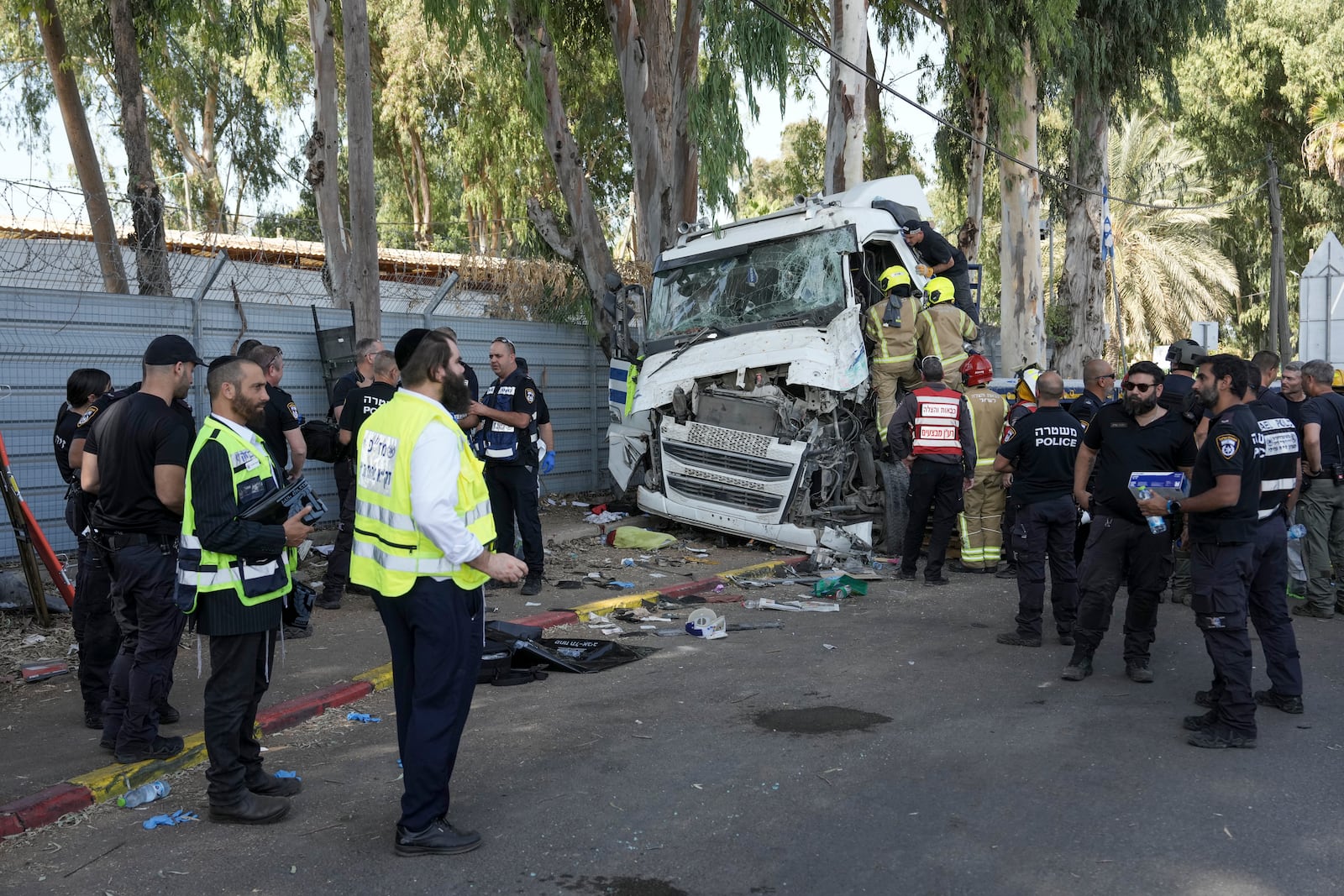 Israeli police and rescue workers climb on a truck to inspect the body of a driver that rammed into a bus stop near the headquarters of Israel's Mossad spy agency, wounding dozens of people, according to Israel's Magen David Adom rescue service in Tel Aviv, Israel, Sunday, Oct. 27, 2024. (AP Photo/Oded Balilty)