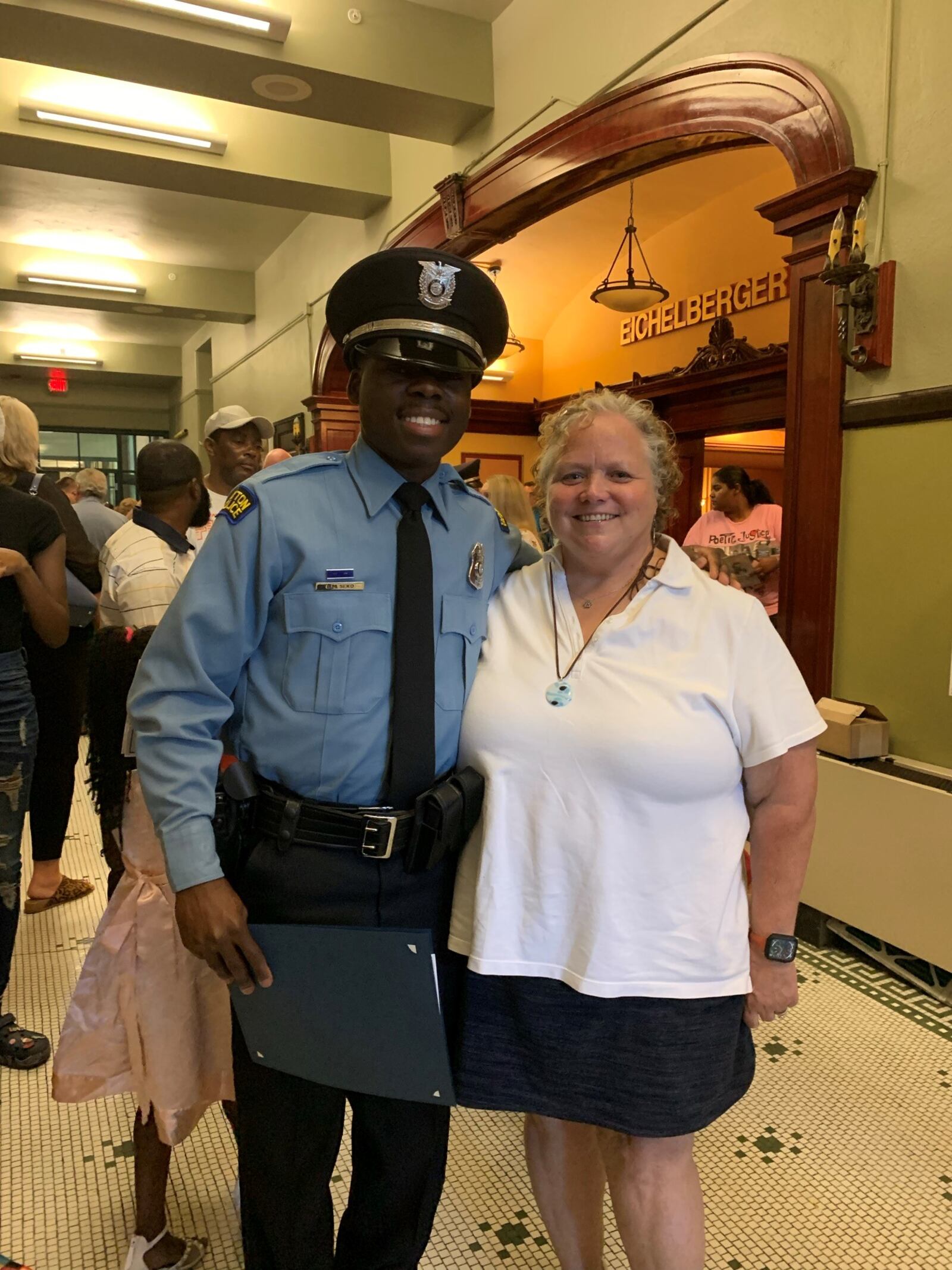 New Dayton Police officer Bibebibyo “Bibe” Seko and Julie Raiff, his former Belmont High School soccer coach and continuing champion at Bibe’s graduation ceremony at Stivers School for the Arts nine evenings ago (Contributed Photo)