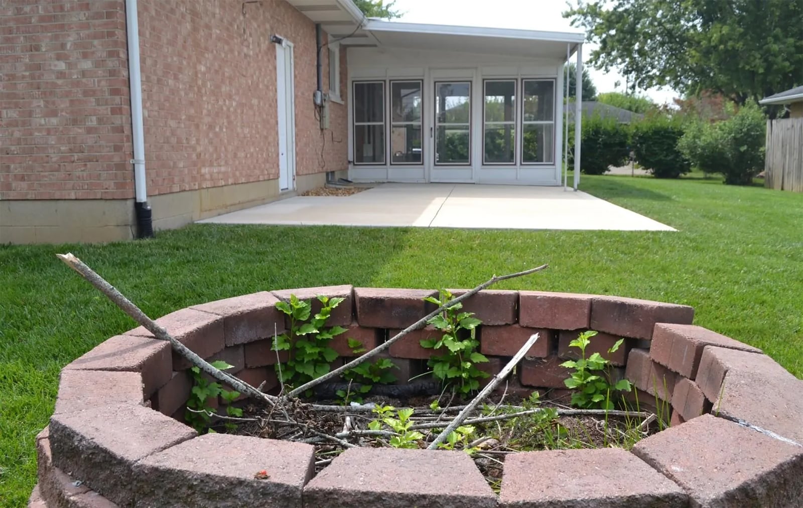 The rear of the home has a full privacy fence, a sunroom with attached concrete patio and a firepit.