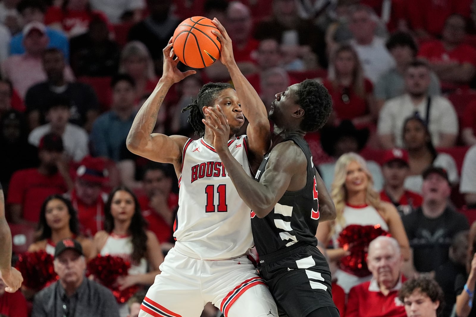 Houston's Joseph Tugler (11) looks to pass the ball as Cincinnati's Aziz Bandaogo defends during the first half of an NCAA college basketball game Saturday, March 1, 2025, in Houston. (AP Photo/David J. Phillip )